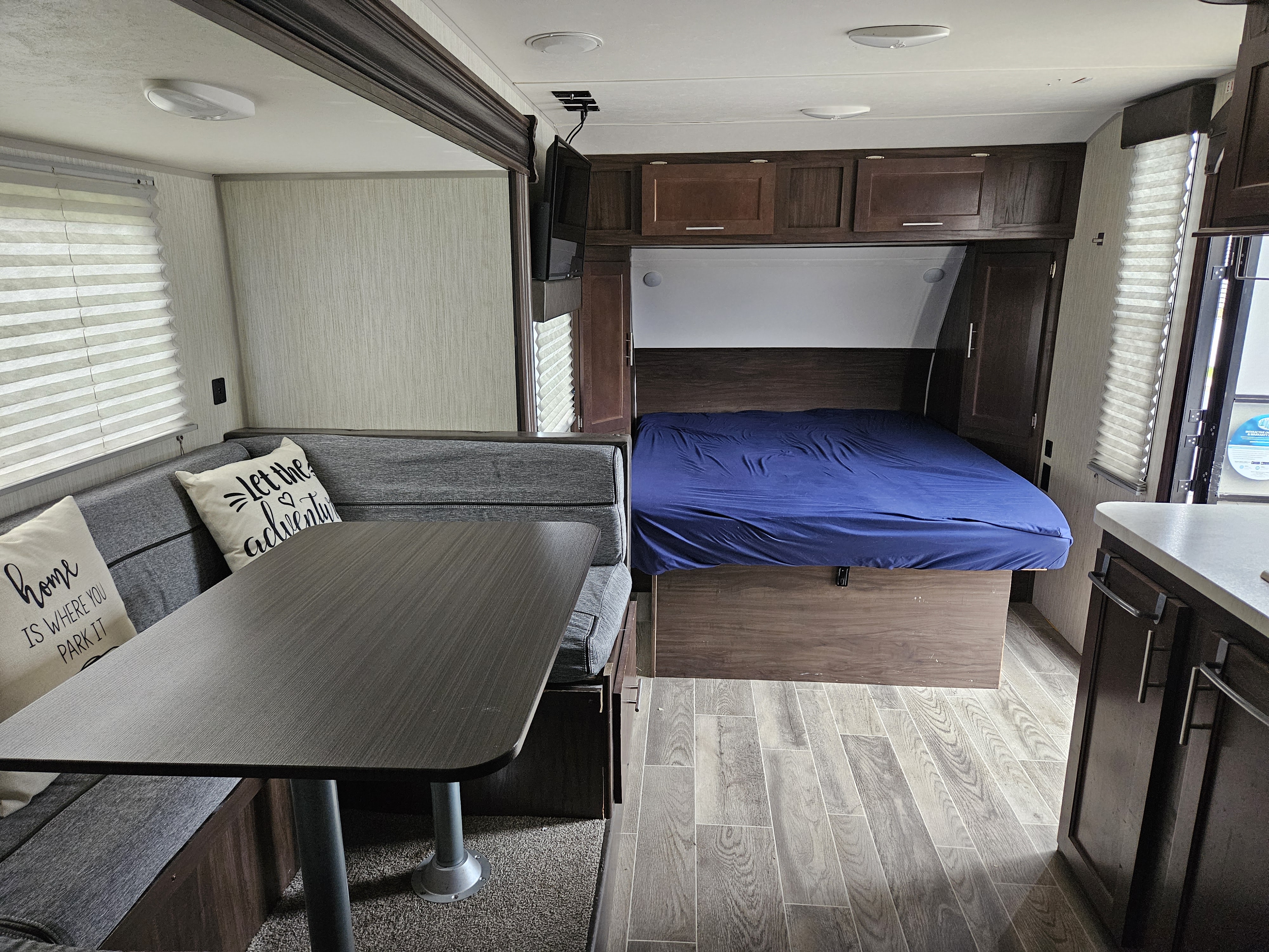 RV rental interior featuring a cozy dining area, bedroom with a blue bed, TV, and compact kitchen counter.. Forest River Cherokee Wolf Pup 2020