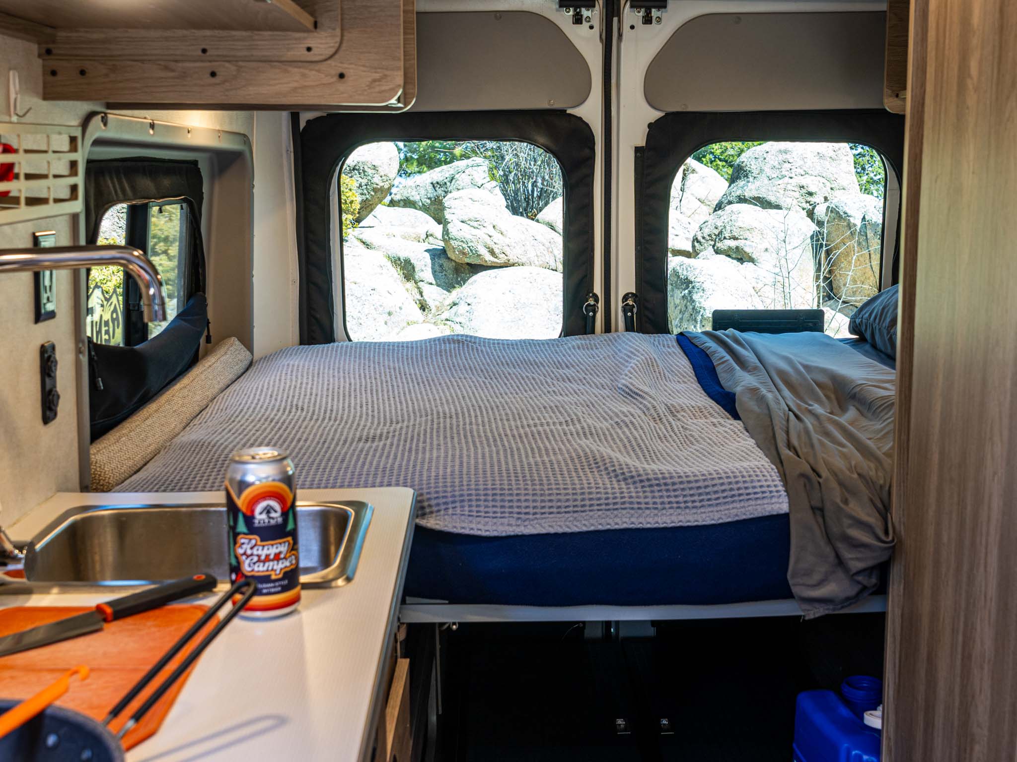 Inside this cozy rv rental: Bed, small kitchen with sink & beer, offering scenic views of large rocks from the camper van.. Winnebago Solis 2022