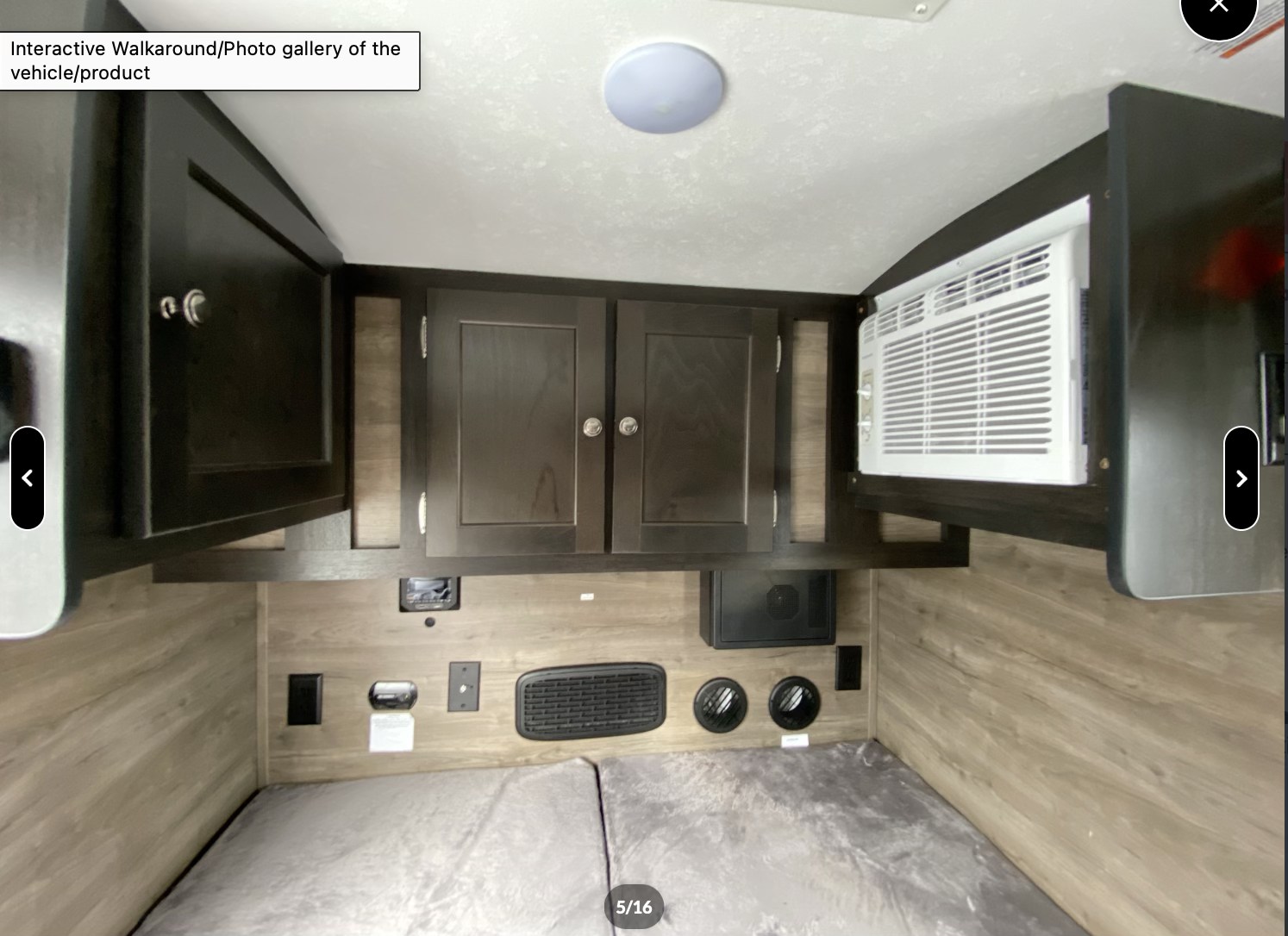 Explore this rv rental's cozy sleeping area. Features bed, overhead cabinets, AC unit, and essential wall controls.. Braxton Creek Bushwhacker 2022
