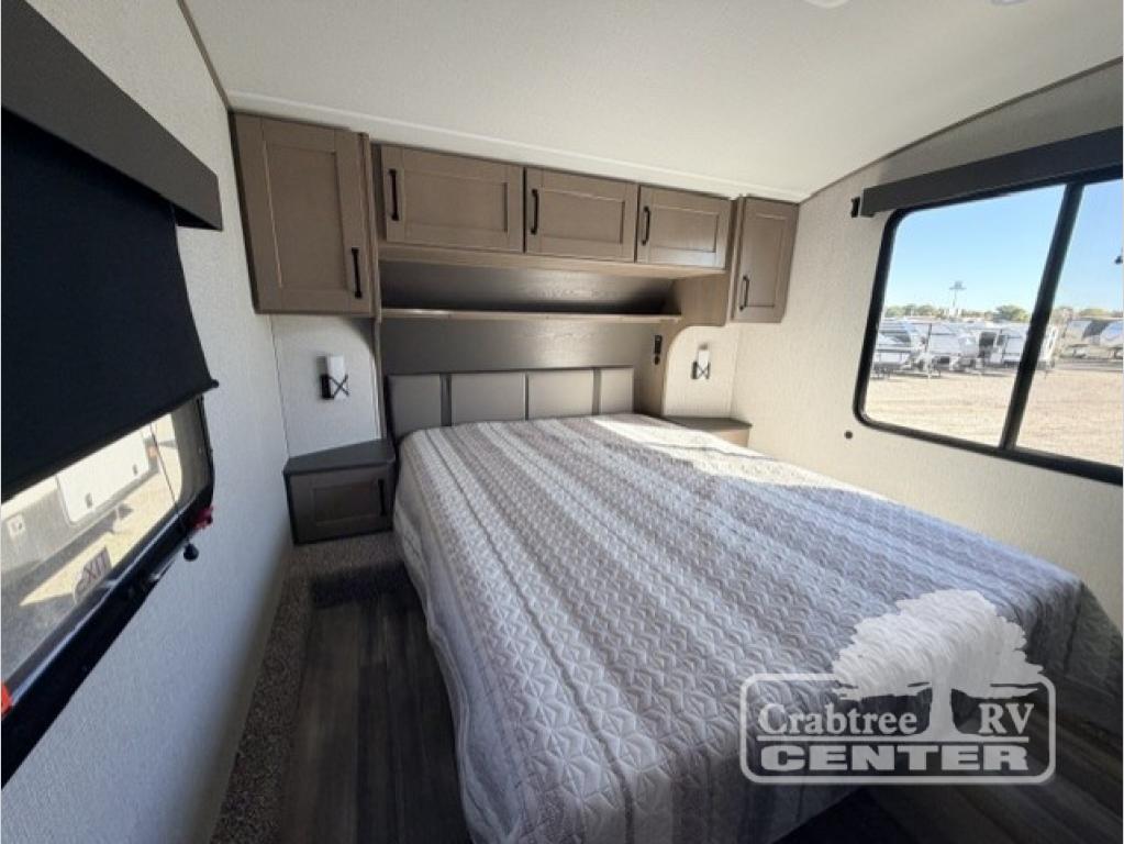 Explore this RV rental's spacious bedroom, featuring a comfortable bed, overhead cabinets, and large windows for bright travels.. Grand Design Reflection 150 2025