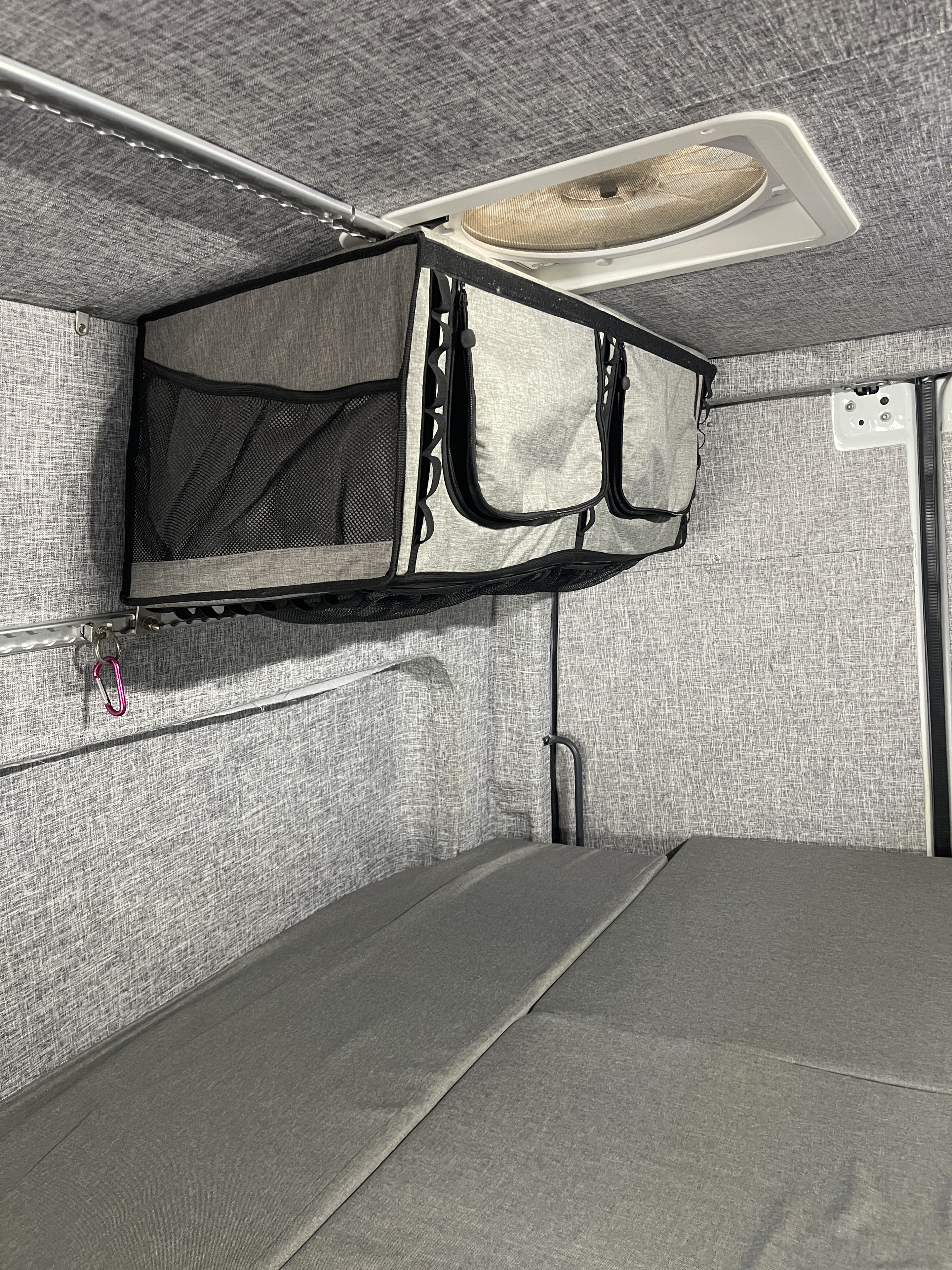 RV rental interior featuring practical overhead storage, a roof vent fan, and modular grey bed cushions for comfortable travel.. MERCEDES SPRINTER 144 2020