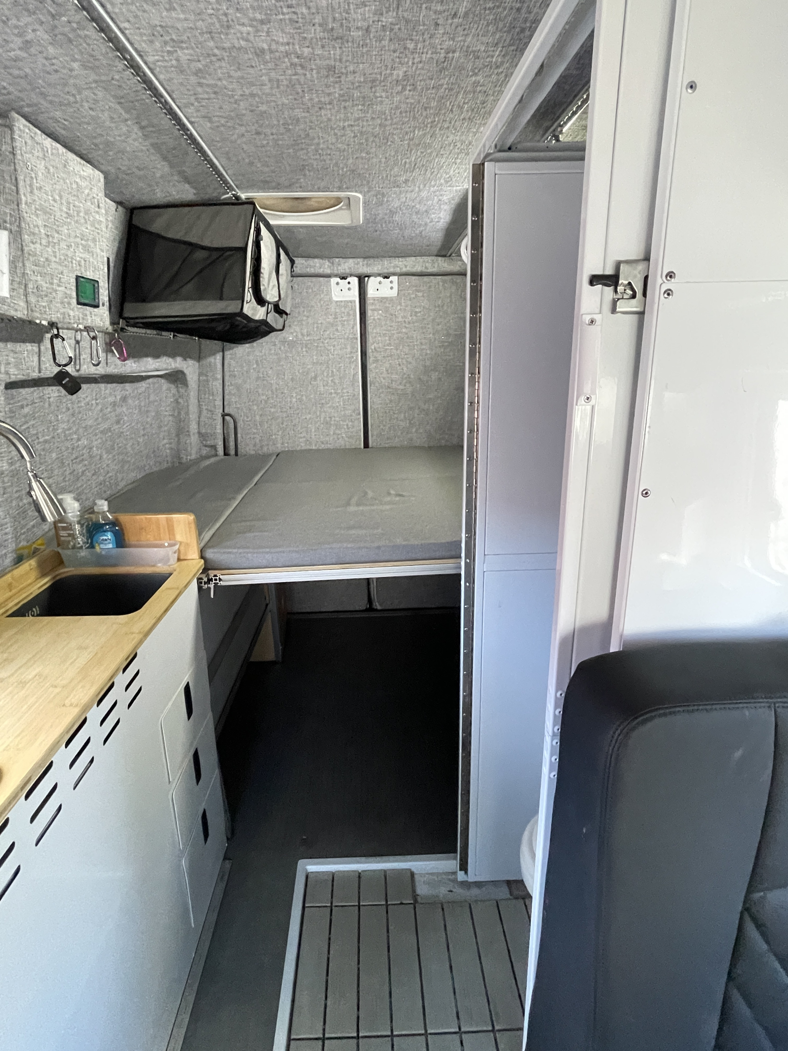 Inside a functional RV rental: compact kitchenette, elevated sleeping area, & clever storage in a modern design.. MERCEDES SPRINTER 144 2020