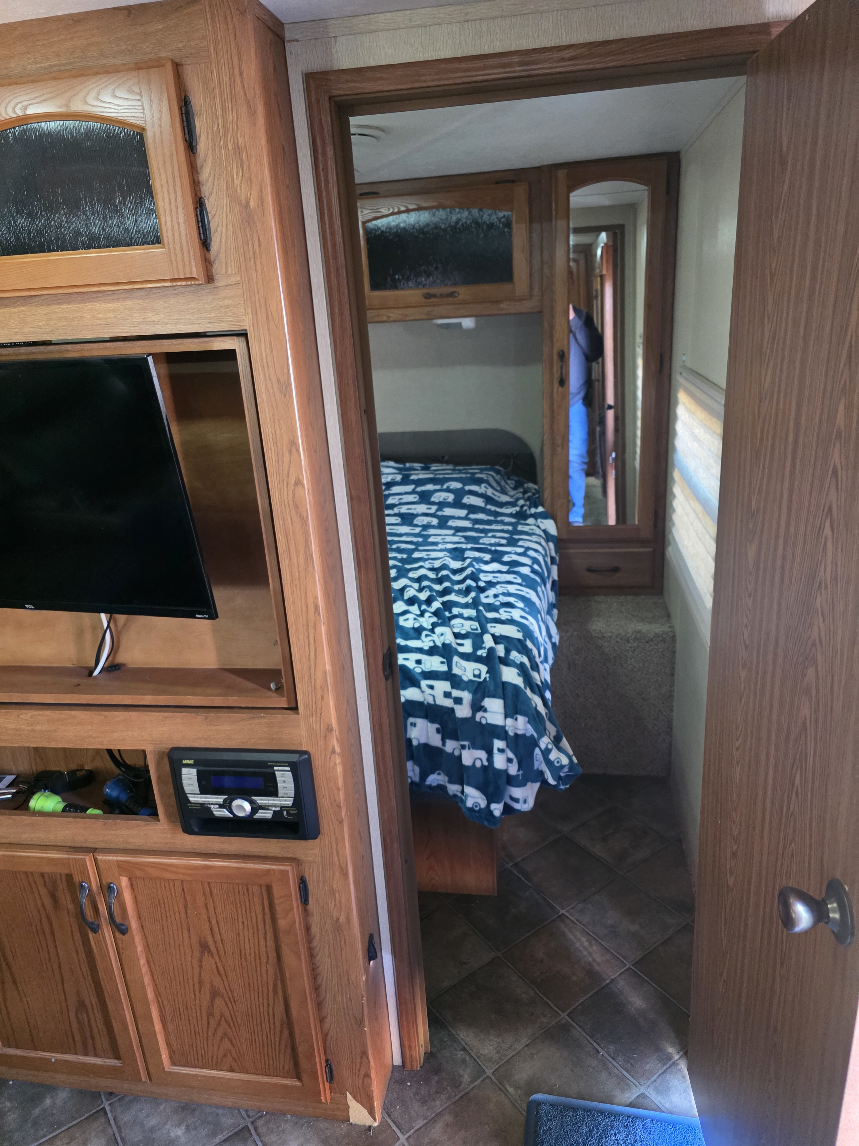 RV rental interior: bedroom with a bed, patterned blanket, mirrored closet, TV, and entertainment system.. Keystone RV Sprinter 2013