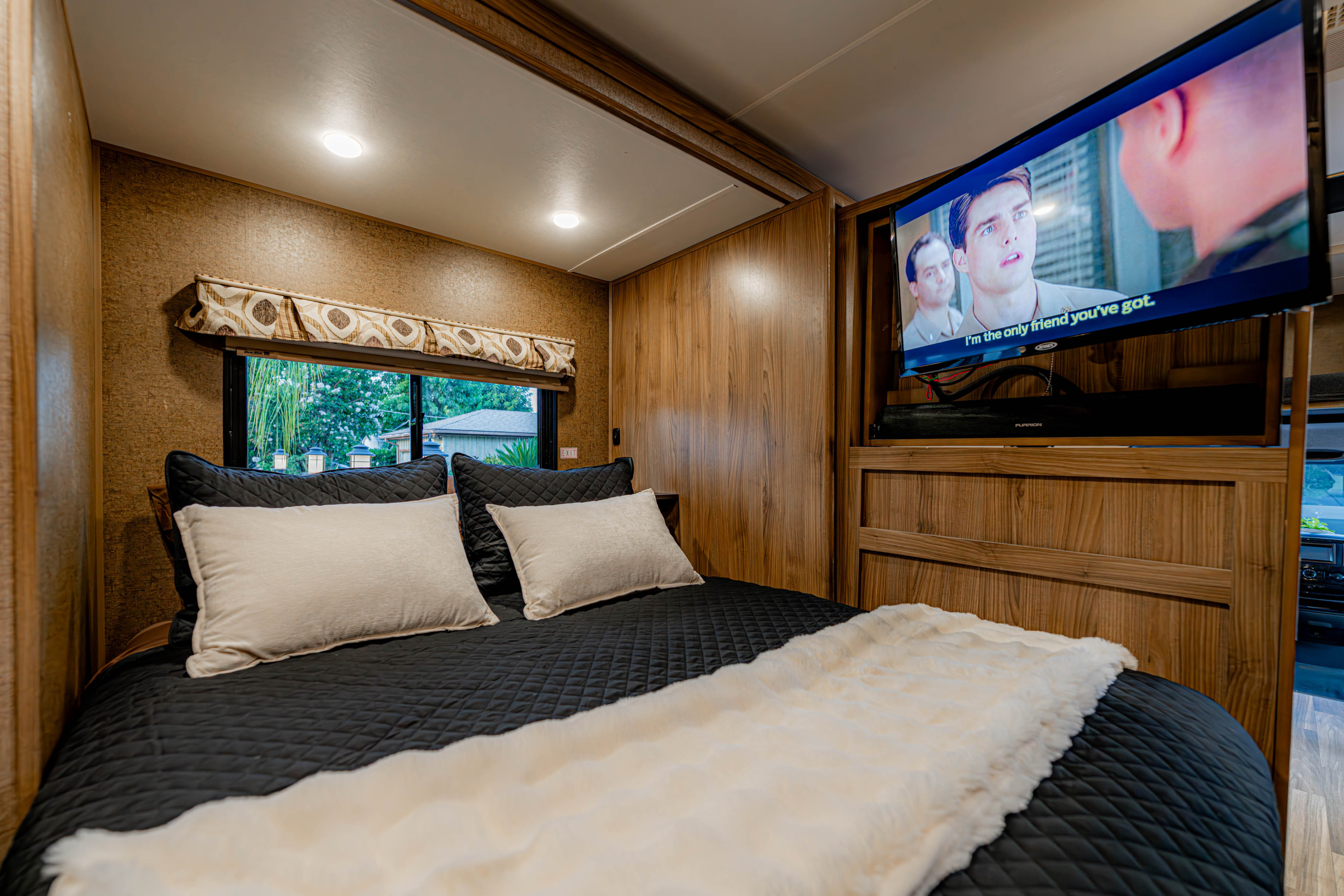 Relax in this RV rental bedroom featuring a comfy bed with soft blankets, a mounted TV, and warm wood-paneled walls.. Coachman Prism 2200 LE 2017
