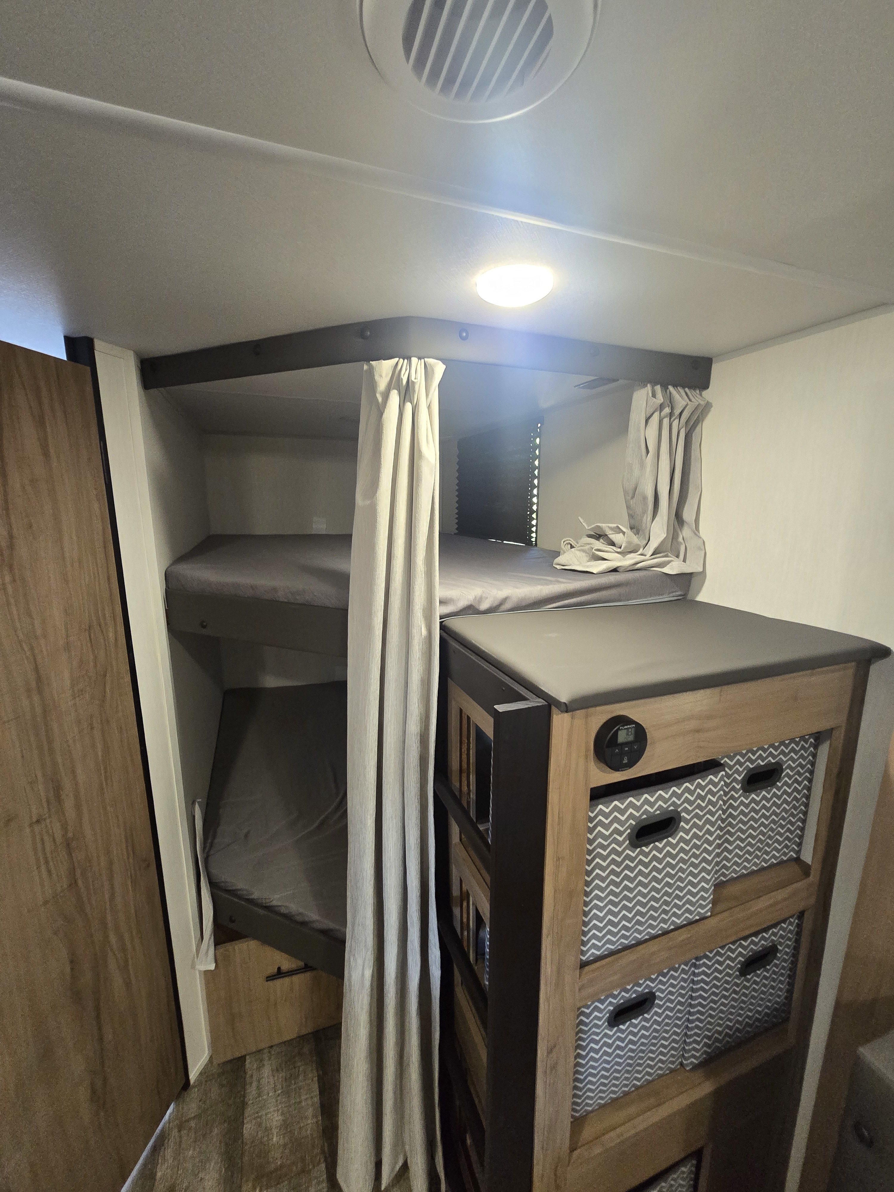 RV rental: Bunk beds with privacy curtains, ceiling light, and storage bins for a family-friendly setup.. Forest River Campsite Reserve 2025