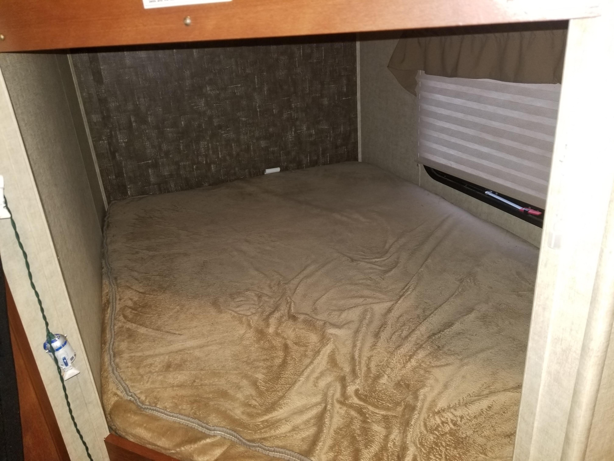 This RV rental bunk bed offers a cozy sleeping space with a plush blanket, patterned wall, and fun R2-D2 string lights.. Heartland RVs Wilderness 2015