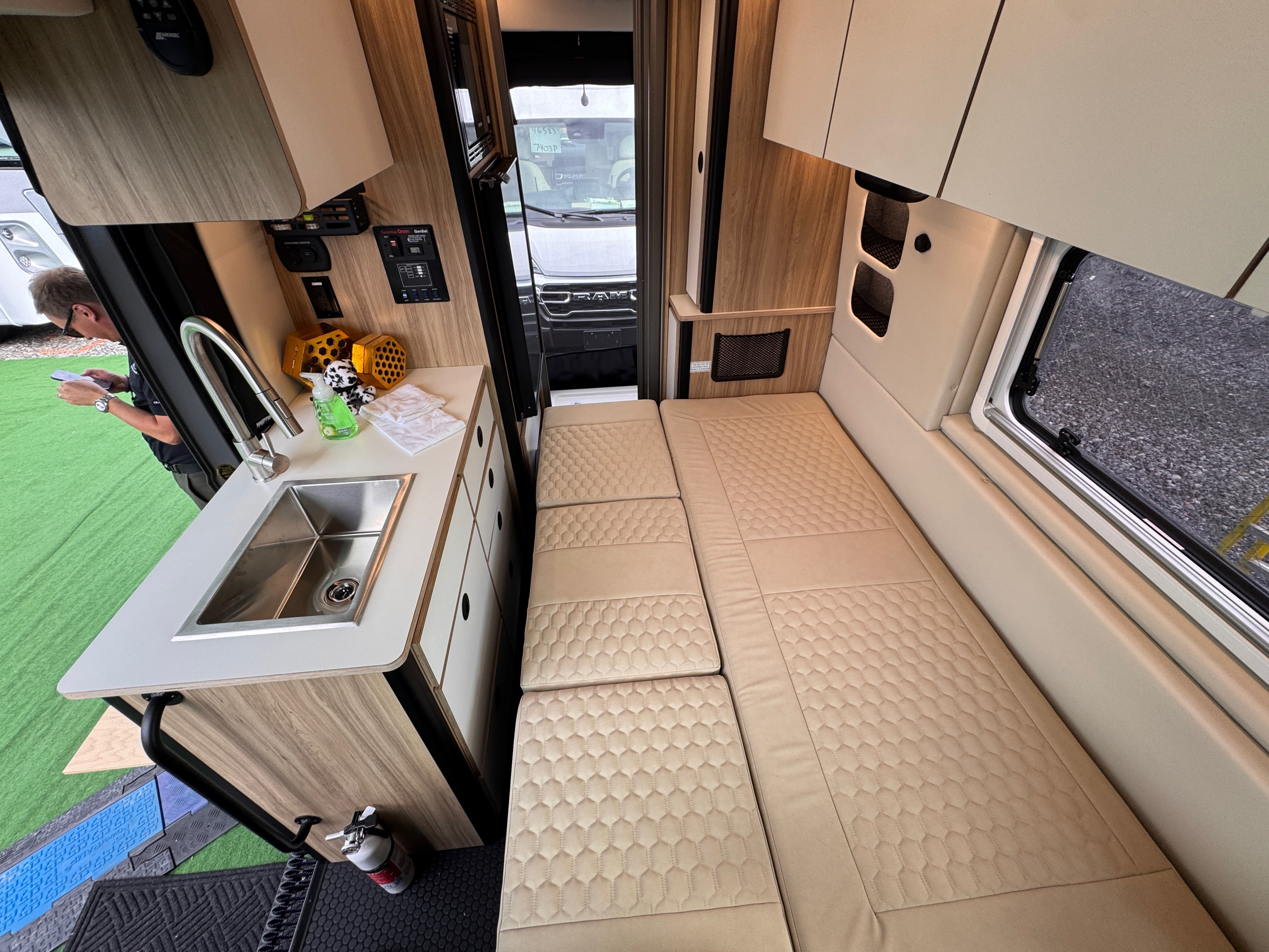 Modern RV rental van interior: compact kitchen, sink, control panels, and a long convertible bed with quilted cushions.. Forest River Coachmen Pixel 2026