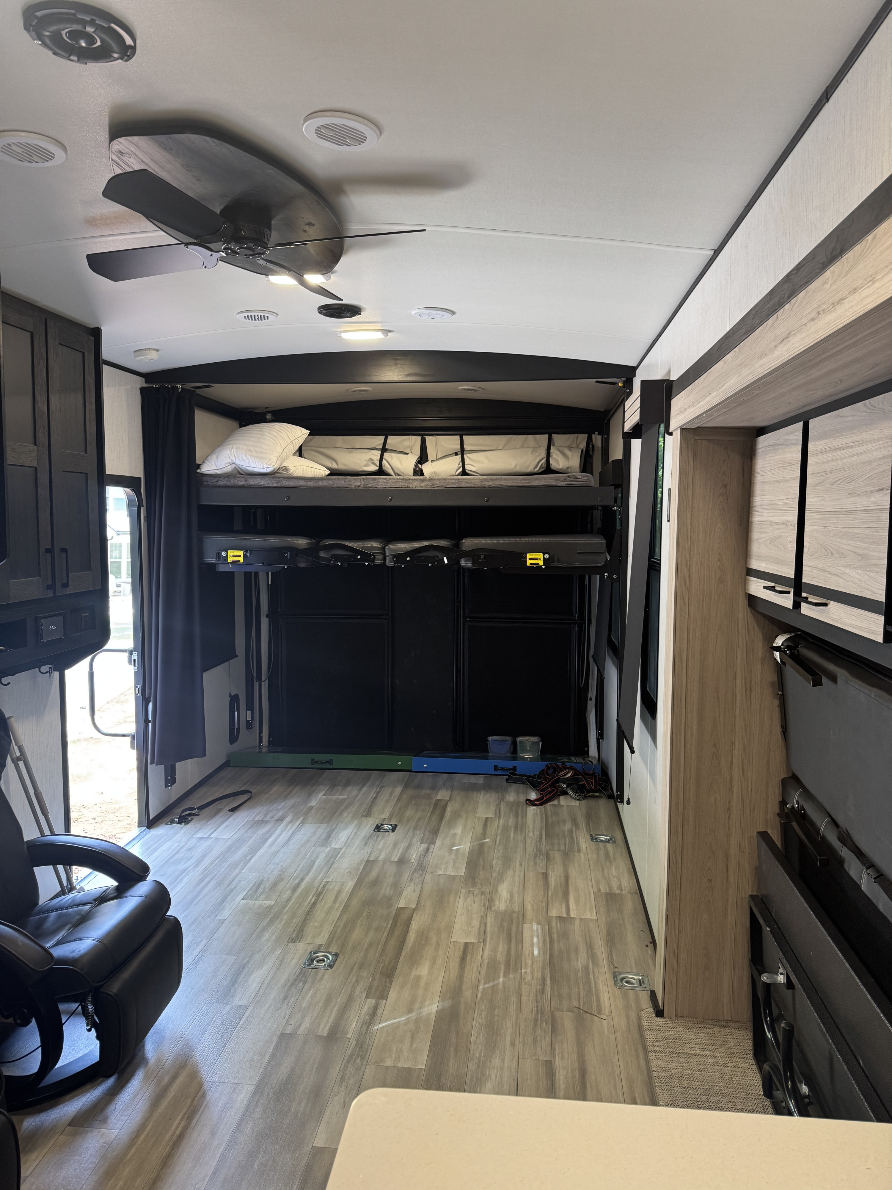 This RV rental interior shows a toy hauler's versatile living space with dropdown bunks, wood-look floor, and open ramp door.. Cruiser Rv Corp Stryker 2022