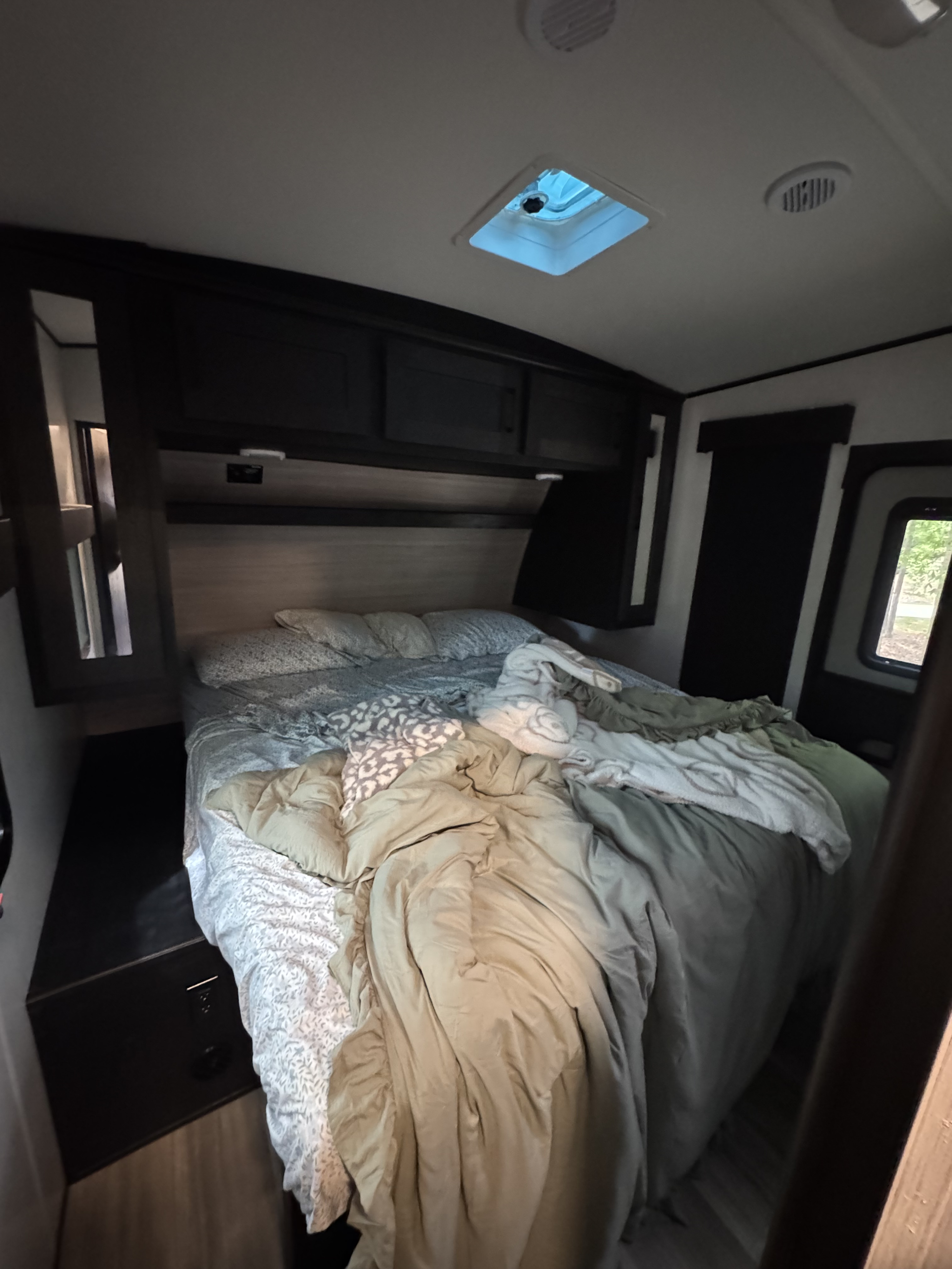 Unmade bed in a cozy RV rental bedroom, featuring overhead storage, a skylight, and power outlets for travelers.. Cruiser Rv Corp Stryker 2022