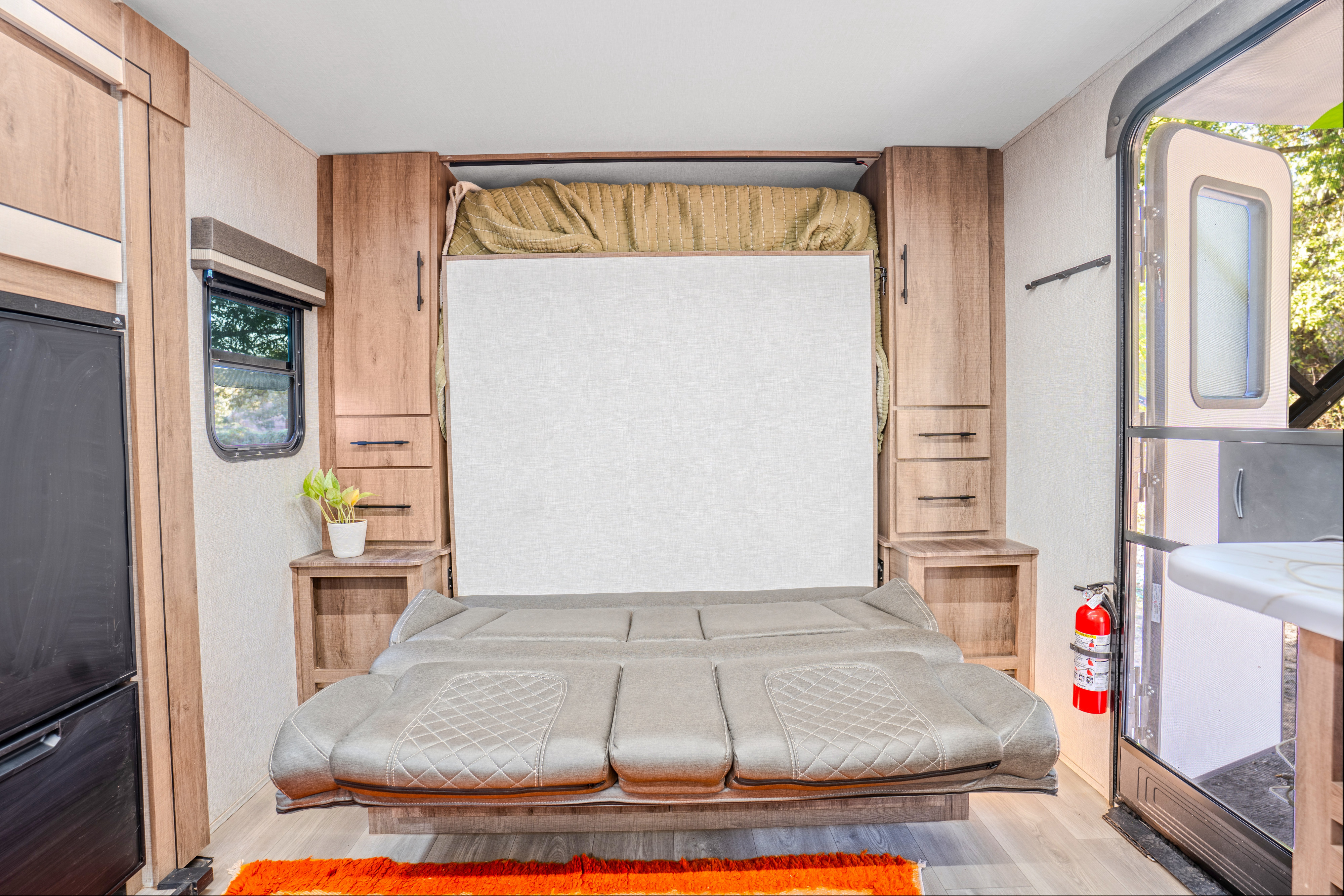 RV rental: Interior shows an upright murphy bed, sofa, cabinetry, window, and open door with a fire extinguisher.. Grand Design Imagine AIM 2024