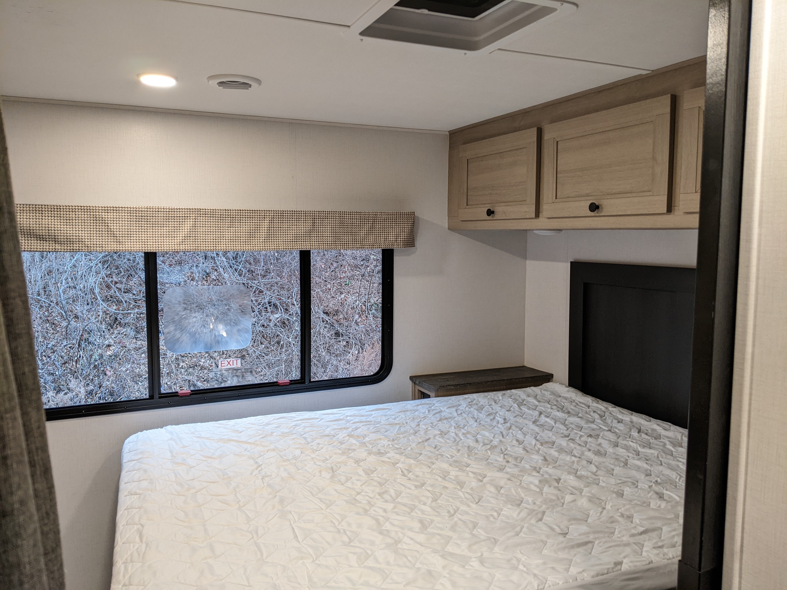 Cozy RV rental bedroom with a comfy bed, overhead storage, and a large window showing an outdoor view.. Forest River Sunseeker 2025