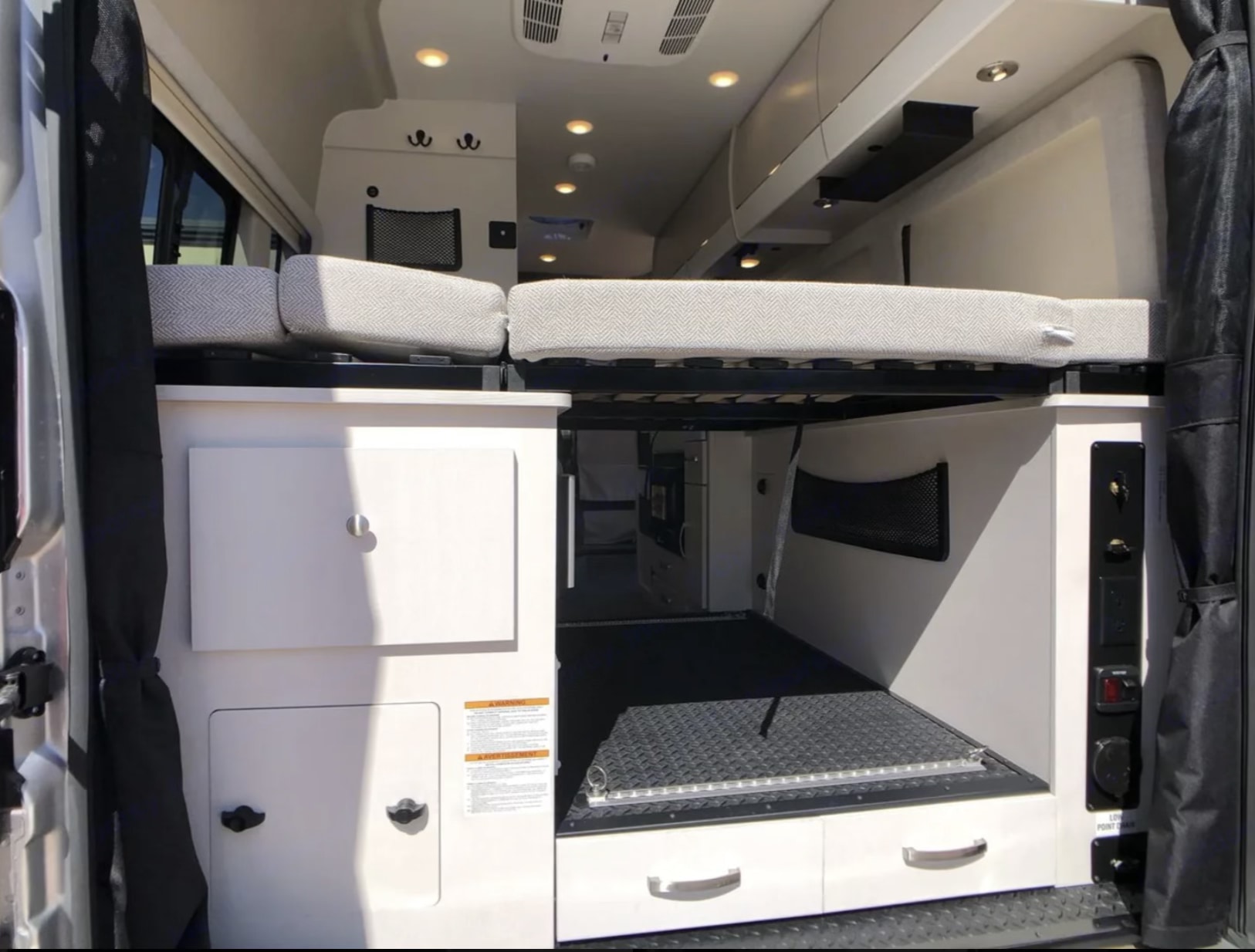 This RV rental shows a versatile interior with a raised bed, ample storage, and cargo space. Perfect for adventure!. Entegra Coach Ethos 2025
