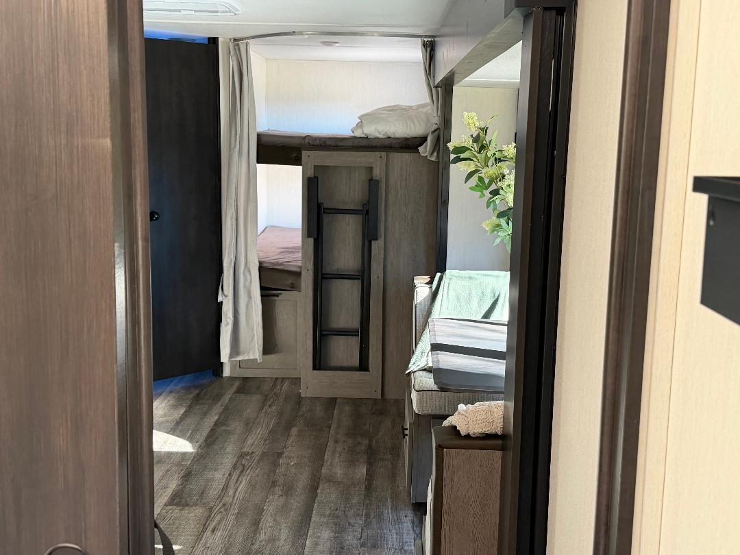 RV rental interior: Modern bunk beds, dinette, and living area visible in this compact camper space.. Forest River Cherokee Alpha Wolf 2025