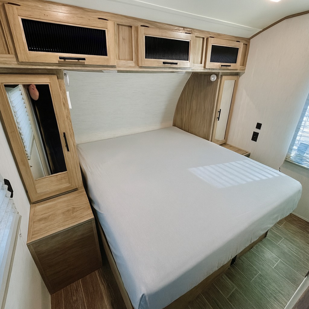 This rv rental bedroom shows a comfortable bed, overhead storage, and mirrored cabinets in a compact interior.. Forest River Cherokee Alpha Wolf 2022