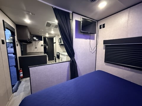 Cozy rv rental interior with blue-bedded sleeping area, compact kitchen, and living space. All set for your next adventure!. Jayco Jay Flight SLX Rocky Mountain Edition 2022