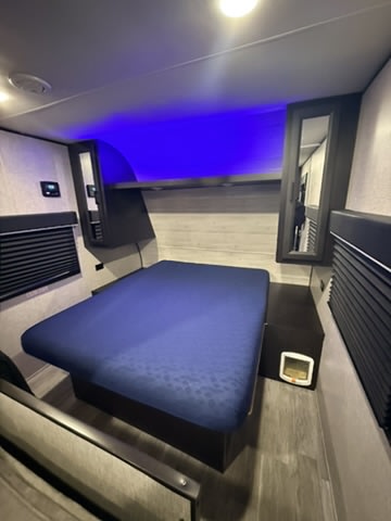 Experience comfort in this RV rental bedroom: blue mattress, overhead storage, and ambient blue lighting.. Jayco Jay Flight SLX Rocky Mountain Edition 2022