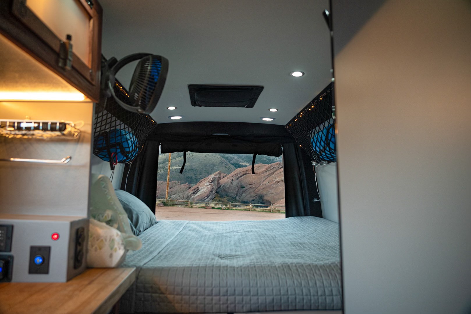 Inside a comfy RV rental: a bed and mountain view through the rear doors, with modern lighting. Great for road trips.. Pleasure-Way Rekon 4x4 2022