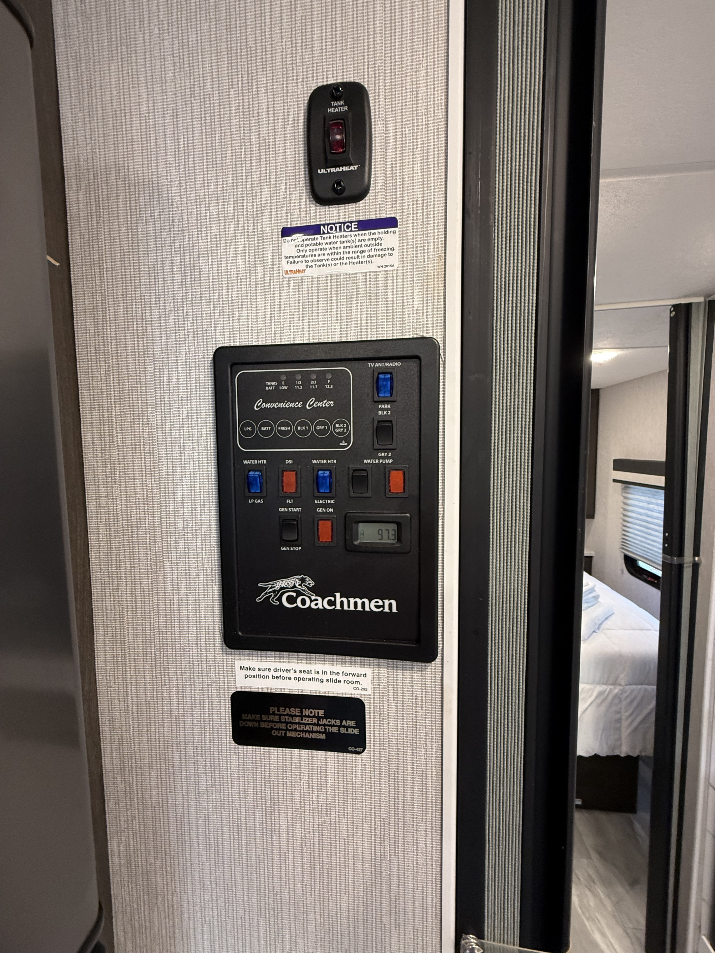 This RV rental's convenience center and tank heater on a wall, displaying tank levels, water pump controls, and safety notices for users.. Forest River Coachmen Pursuit 2024