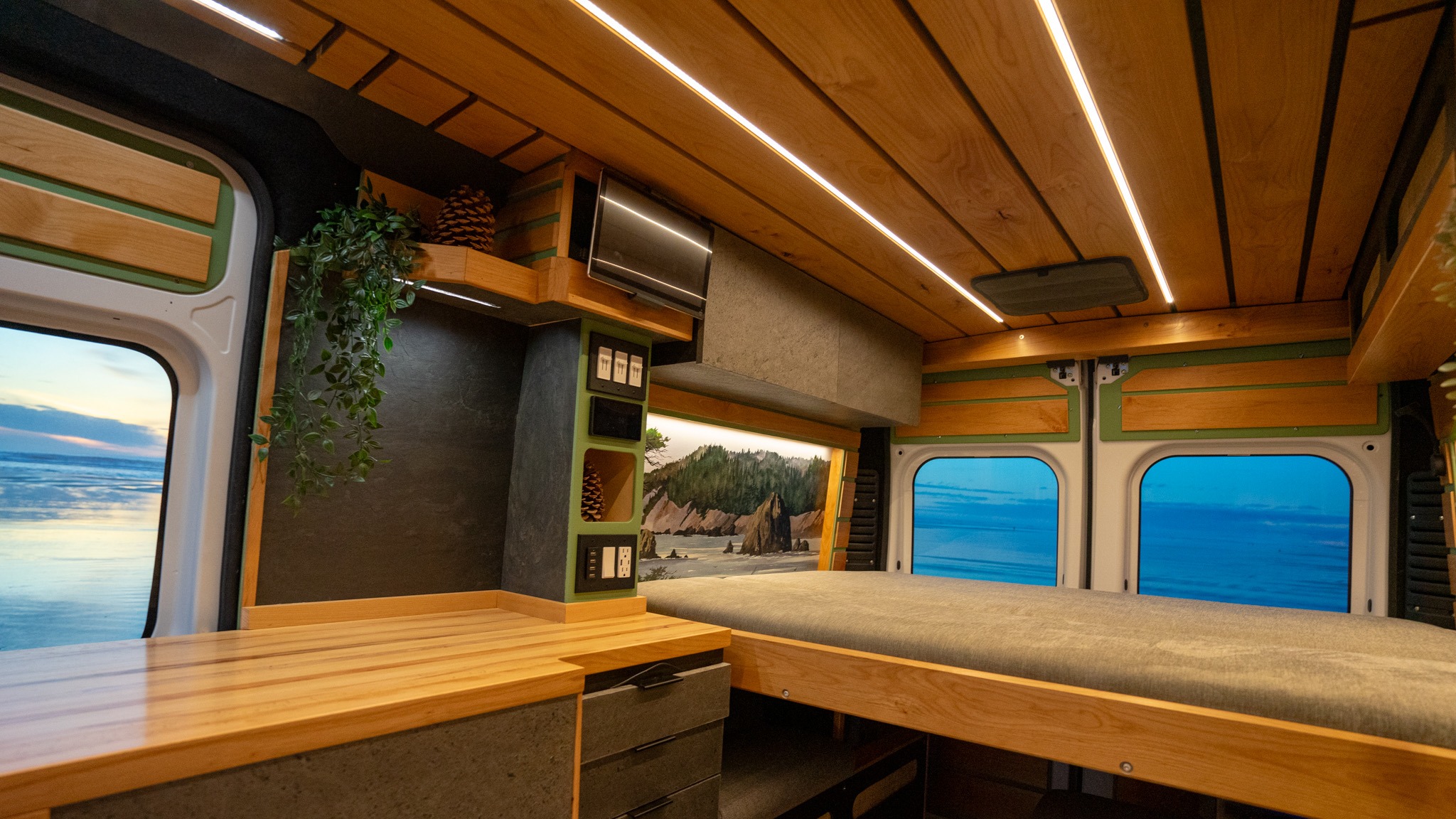This stylish RV rental interior features a custom wood ceiling with bright LED lights, a comfortable bed, functional counter, and vivid nature displays.. Travelcraft Motor Home 2023
