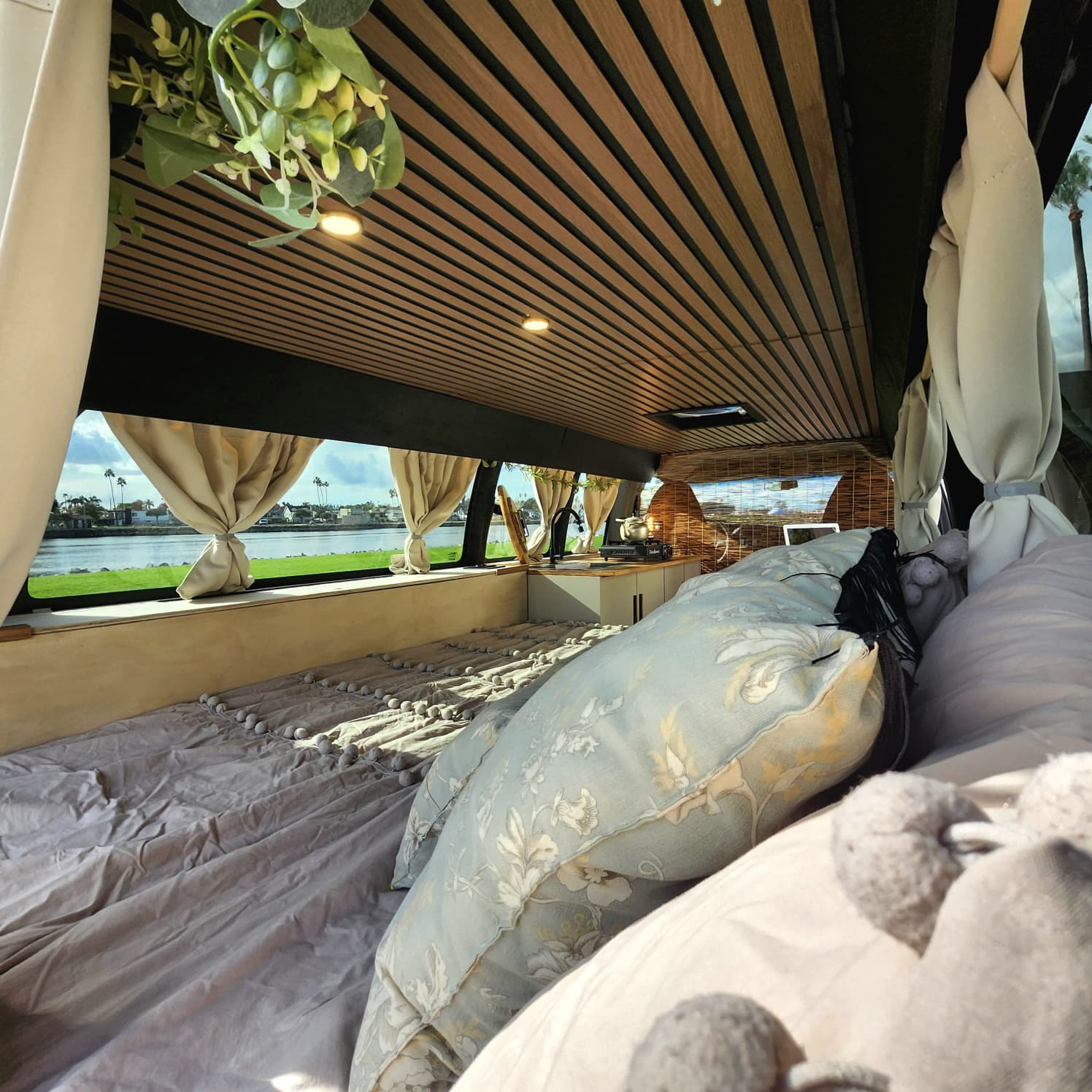 Cozy RV rental interior with a serene waterfront view, perfect for travel. Enjoy this beautifully designed van setup.. Chevy Express 3500 2014