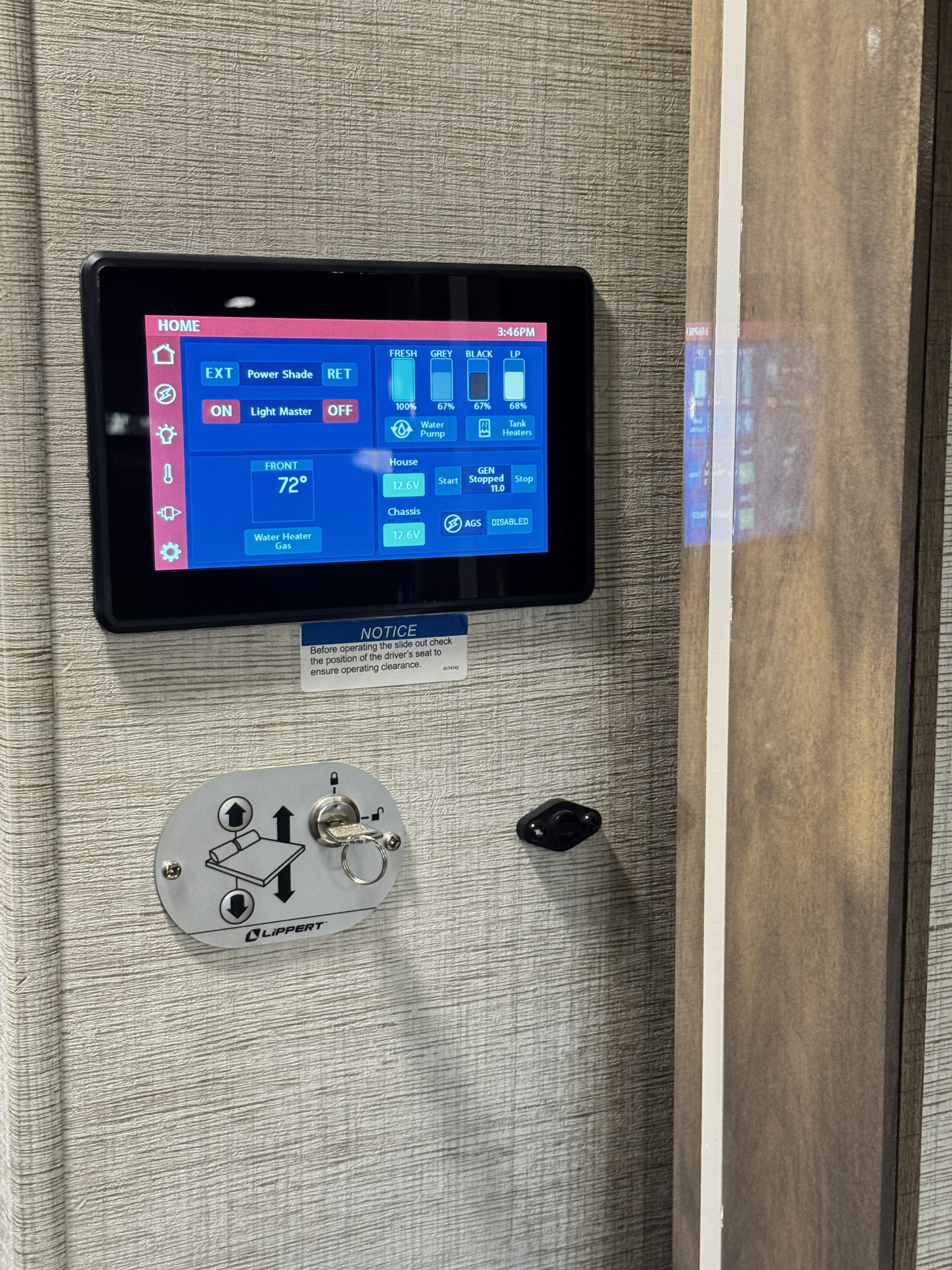 RV rental control panel: digital display with tank levels, temp, power info, and a physical Lippert slide-out key switch.. Entegra Coach Qwest 2023