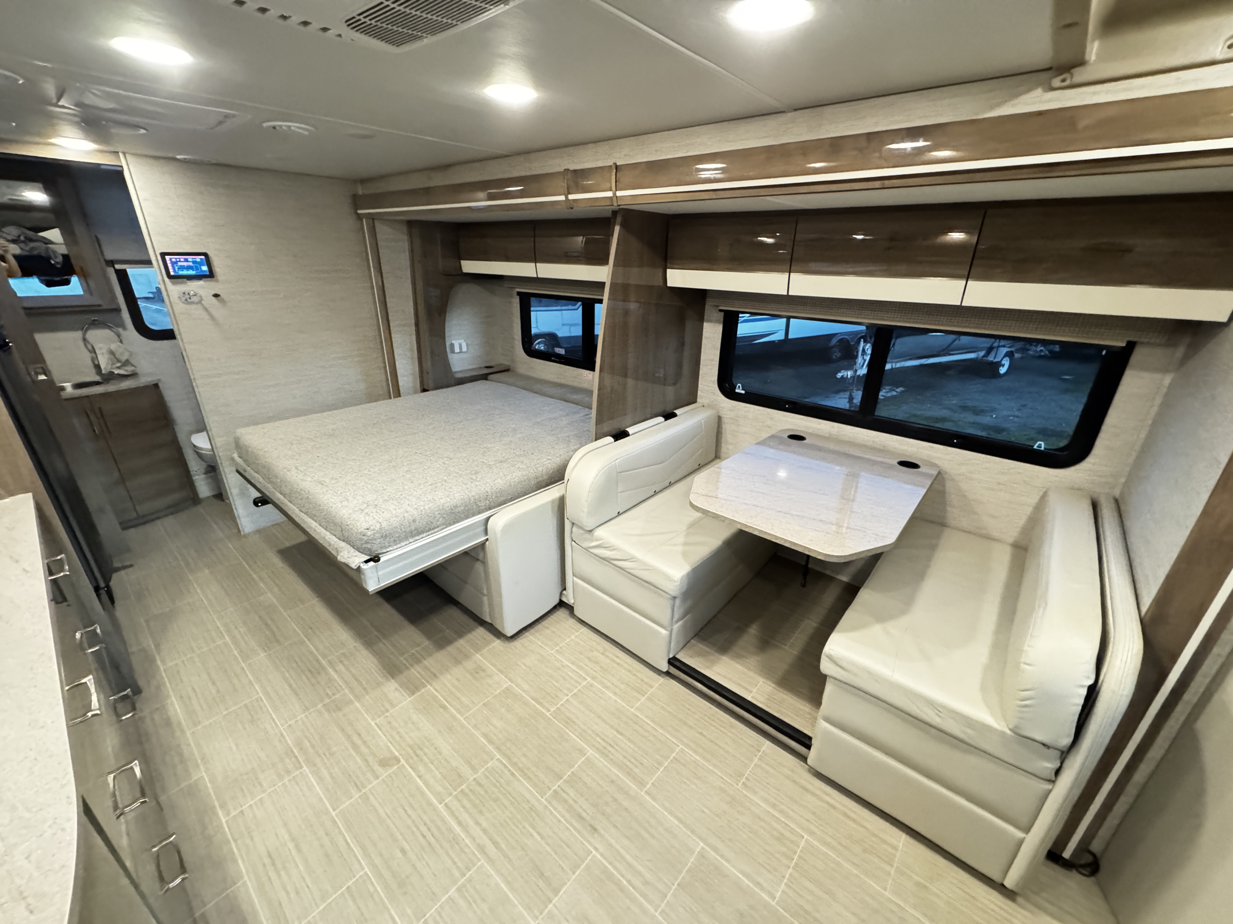 Modern RV rental interior with a pull-out bed, comfortable dinette, and compact kitchen/bathroom area.. Entegra Coach Qwest 2023
