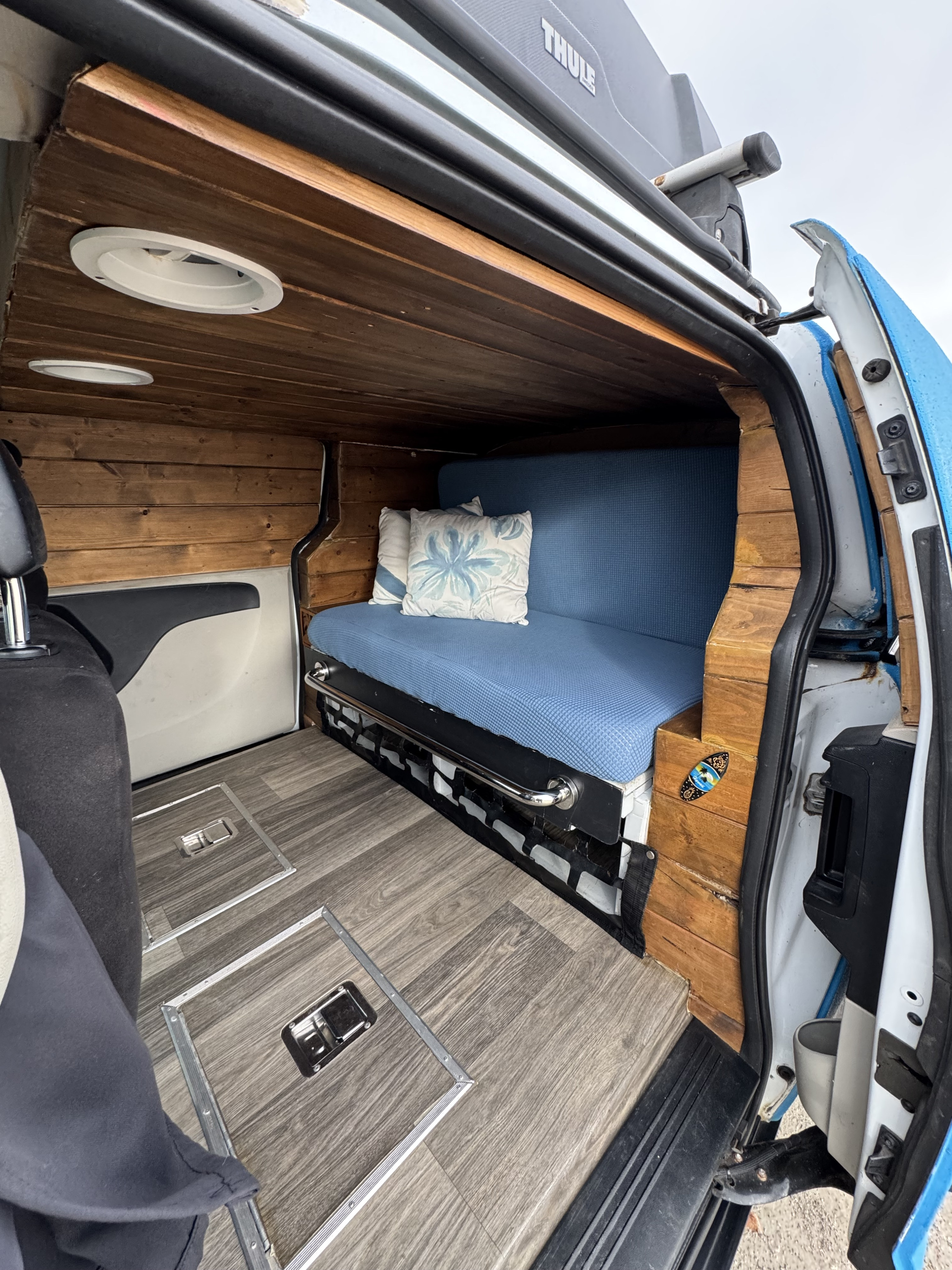 Cozy van interior for your next rv rental adventure! Features wood paneling, comfy blue bench, and floor storage.. Ram C/V Tradesman 2014