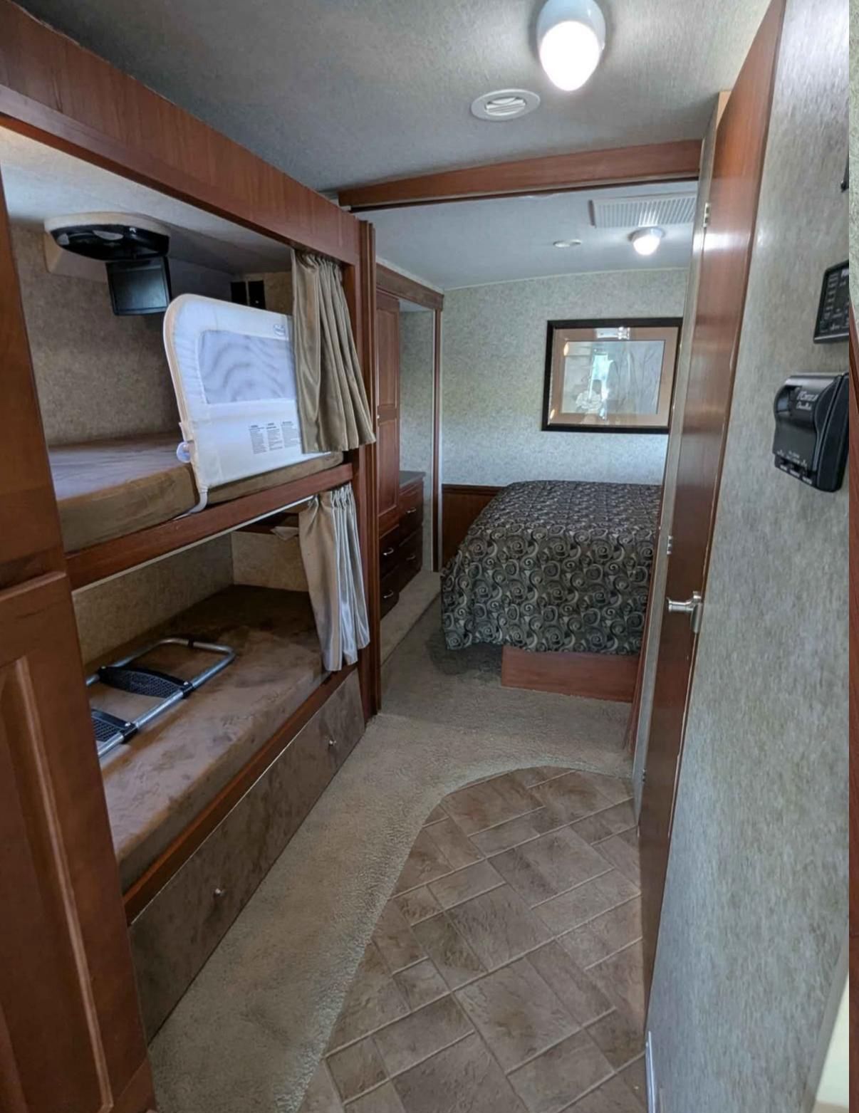 RV rental bedroom with family-friendly bunk beds (safety rail, ladder) and a private master bed, offering comfortable sleeping arrangements.. Itasca Sunstar 2011