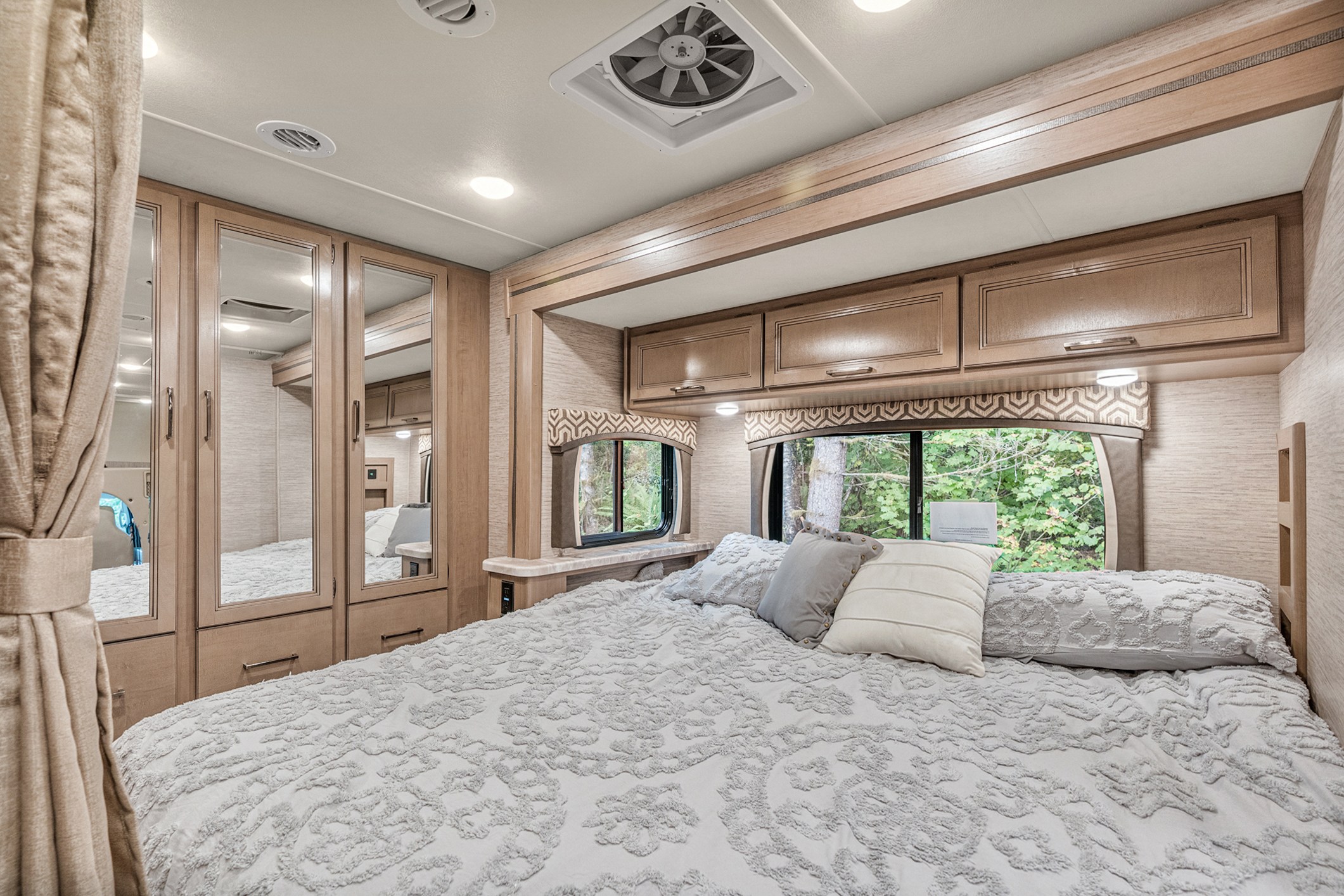 Spacious and modern RV rental bedroom with a comfy bed, mirrored closets, and nature views for relaxing journeys.. Thor Motor Coach Chateau 27R 2022