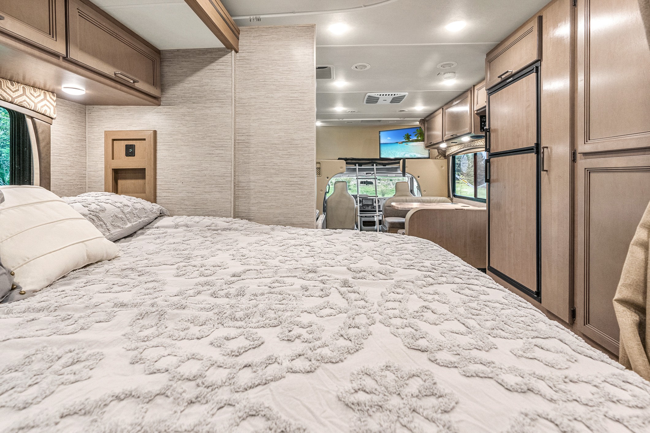 Explore the inviting interior of this RV rental, featuring a comfortable bedroom and a well-equipped living and dining space.. Thor Motor Coach Chateau 27R 2022