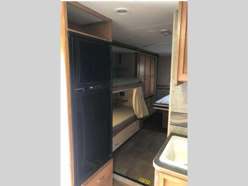 This rv rental offers a compact kitchen with a fridge, sink, and comfortable bunk beds for travel convenience.. Winnebago MINNIE WINNIE 31H 2016