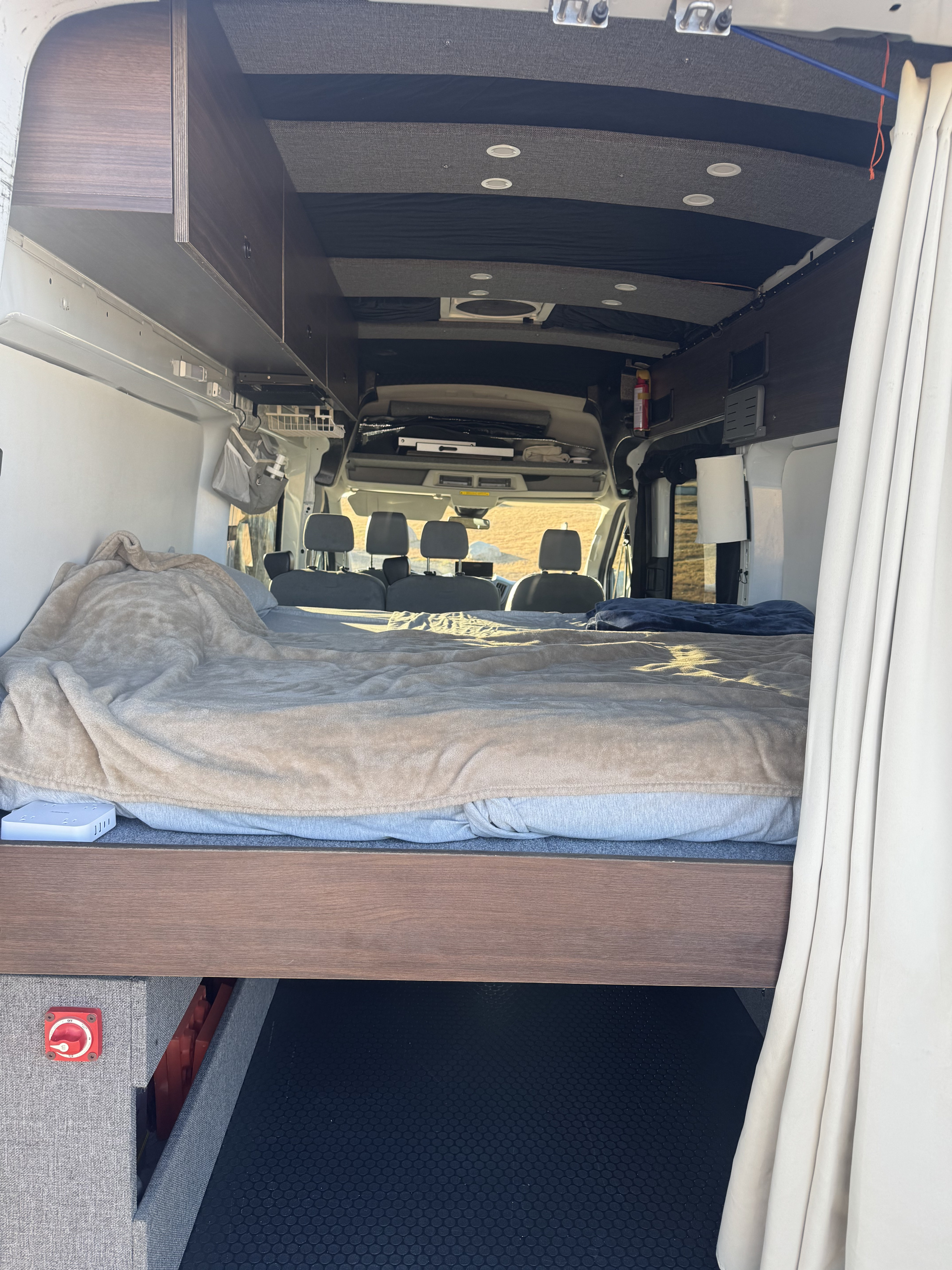 Inside this inviting RV rental: A comfy van bed, overhead storage, and a view to adventure from the sleeping area.. Ford Transit 2018