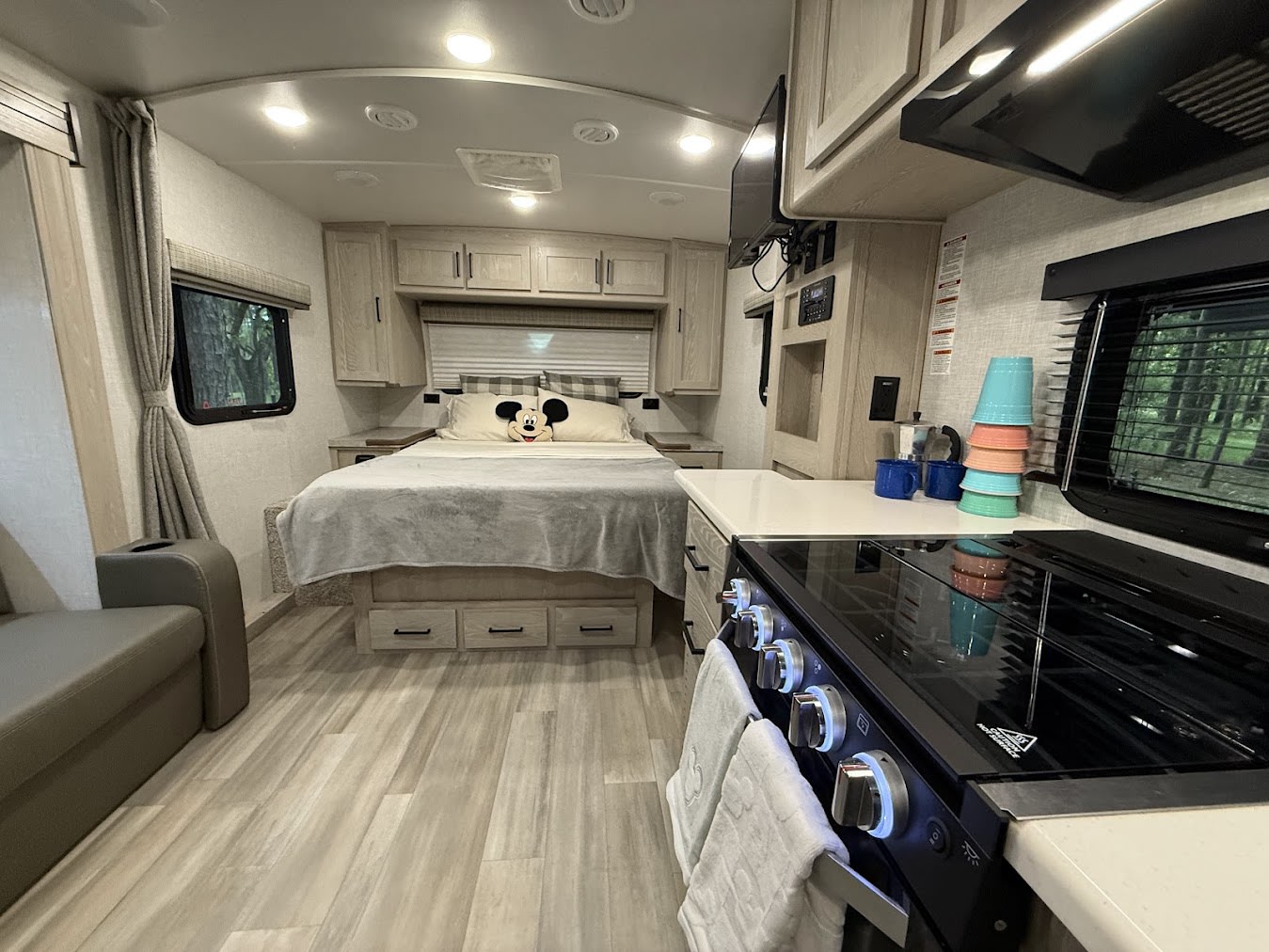 Bright and modern RV rental interior featuring a bedroom with Mickey pillow, compact kitchen, and living space. Ready for adventure!. Forest River Flagstaff Micro Lite 2022