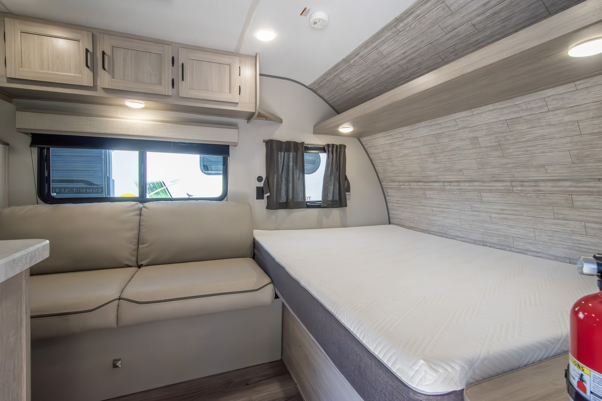 Bright rv rental interior with a comfortable bed, sofa, overhead cabinets, and windows.. Coachmen Other 2024