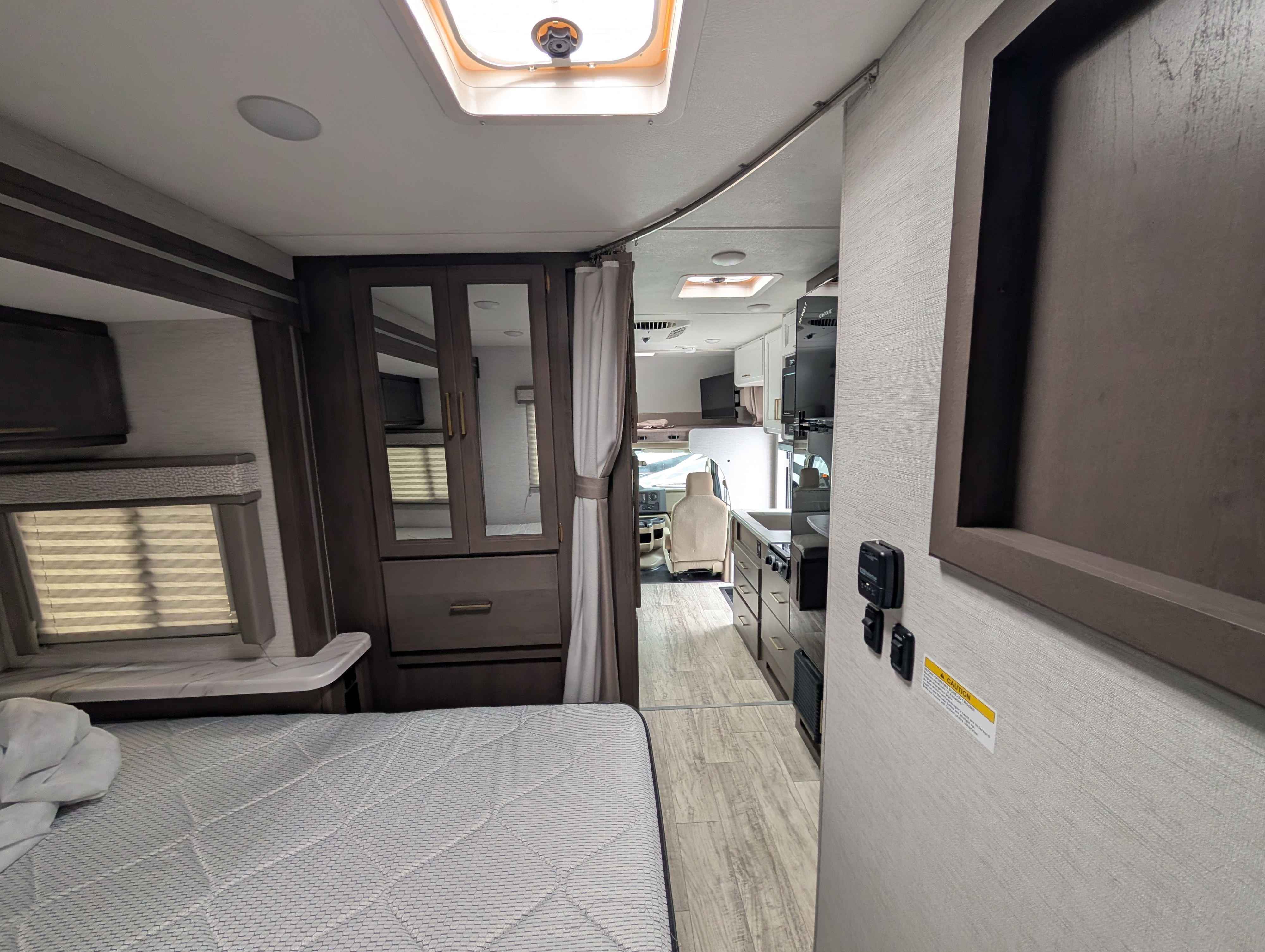 Cozy RV rental interior showing bedroom, kitchen, and driver's cab, with modern finishes and ample storage.. Thor Chateau 2026