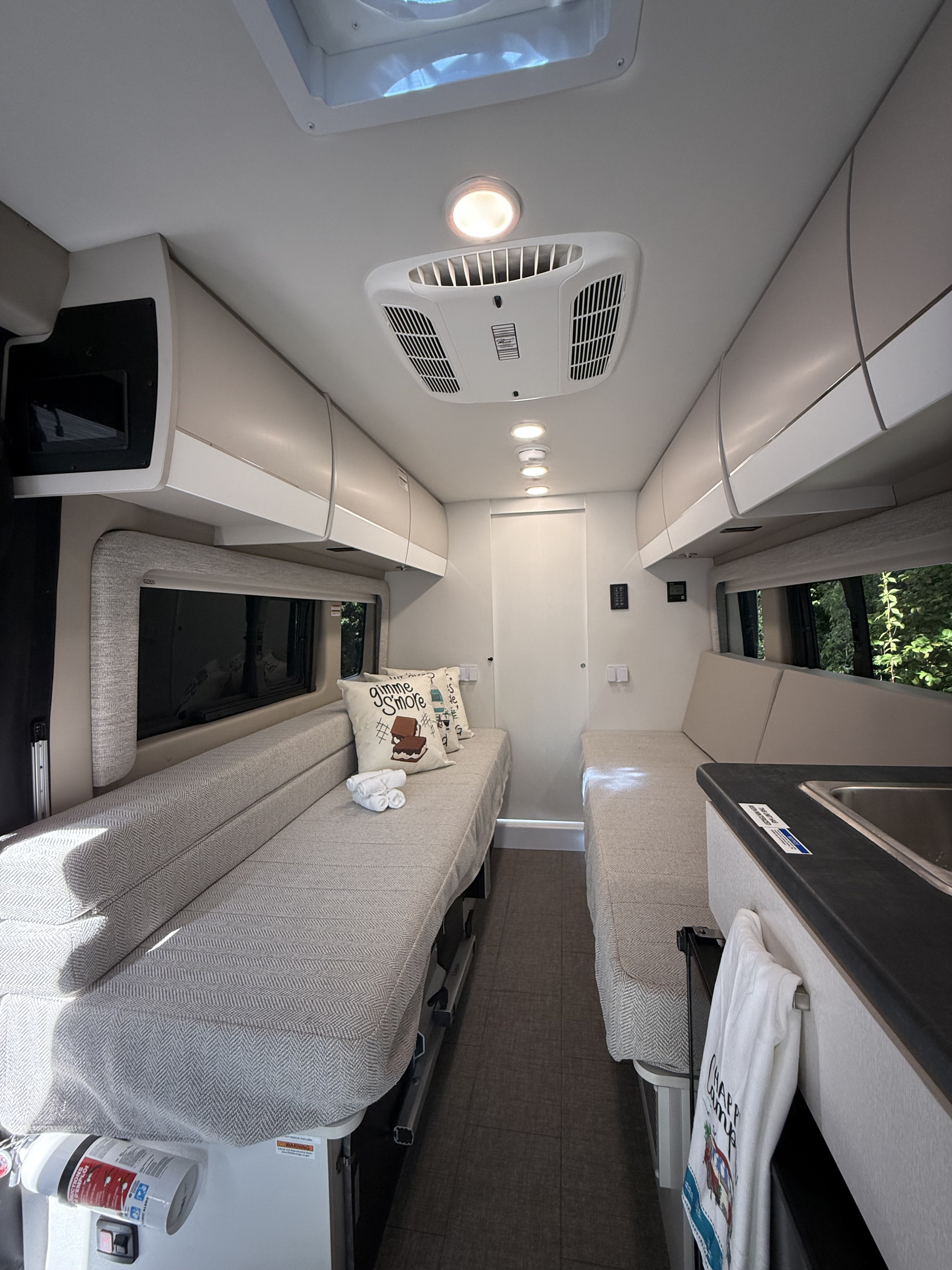 Cozy RV rental interior featuring twin beds, overhead storage, compact kitchen amenities, and a bright, functional living space.. Entegra Coach Ethos 2025