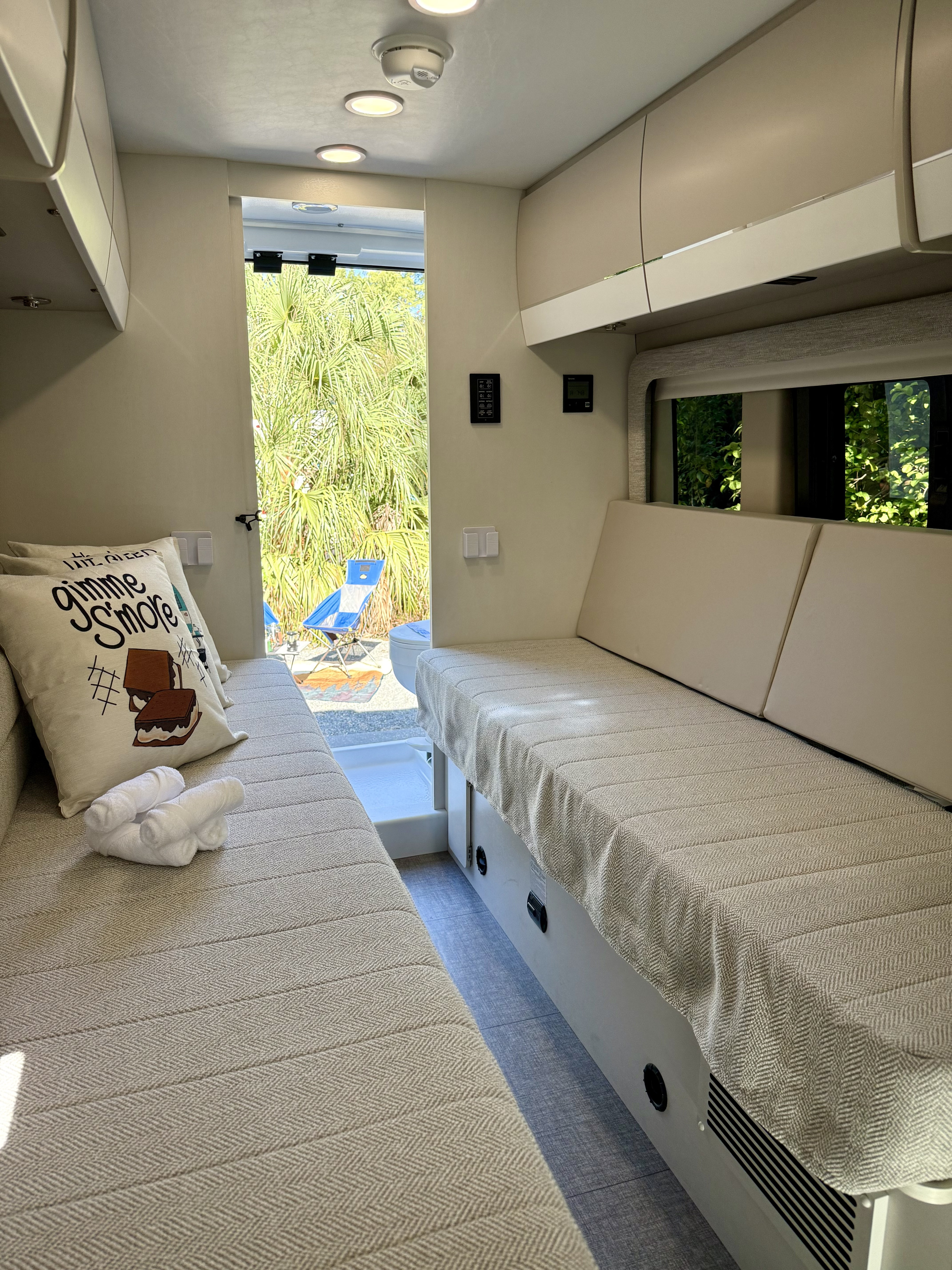 Bright rv rental interior featuring comfortable benches, overhead storage, and an open view to lush outdoors.. Entegra Coach Ethos 2025