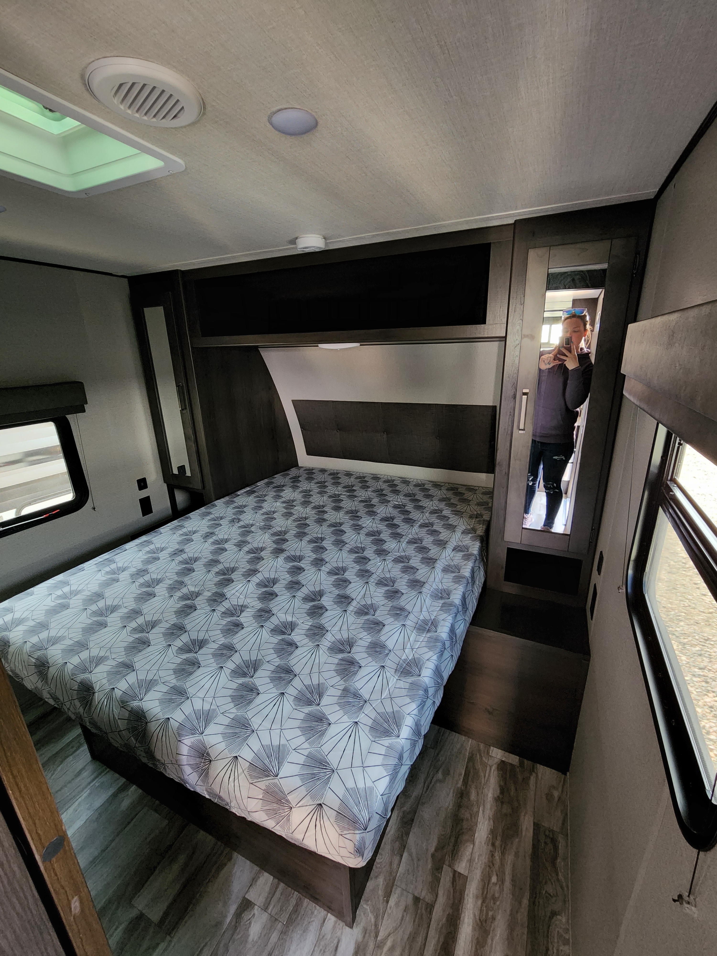 Explore this RV rental bedroom: a comfortable bed, mirrored closet, window, and overhead storage create a cozy travel space.. Grand Design Transcend Xplor 2022