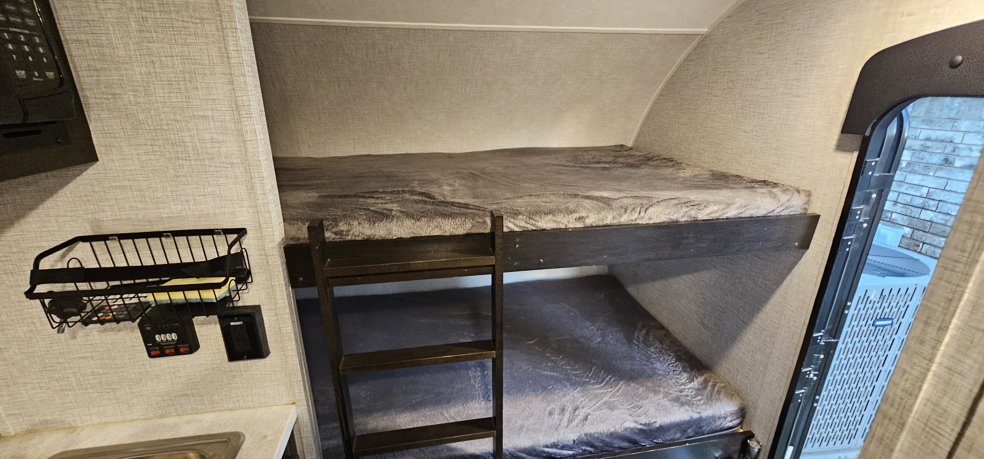 Cozy RV rental bunk beds with a ladder, wall storage, and a glimpse of the kitchen. Ideal for families and travelers.. Braxton Creek Bushwhacker Plus 2022