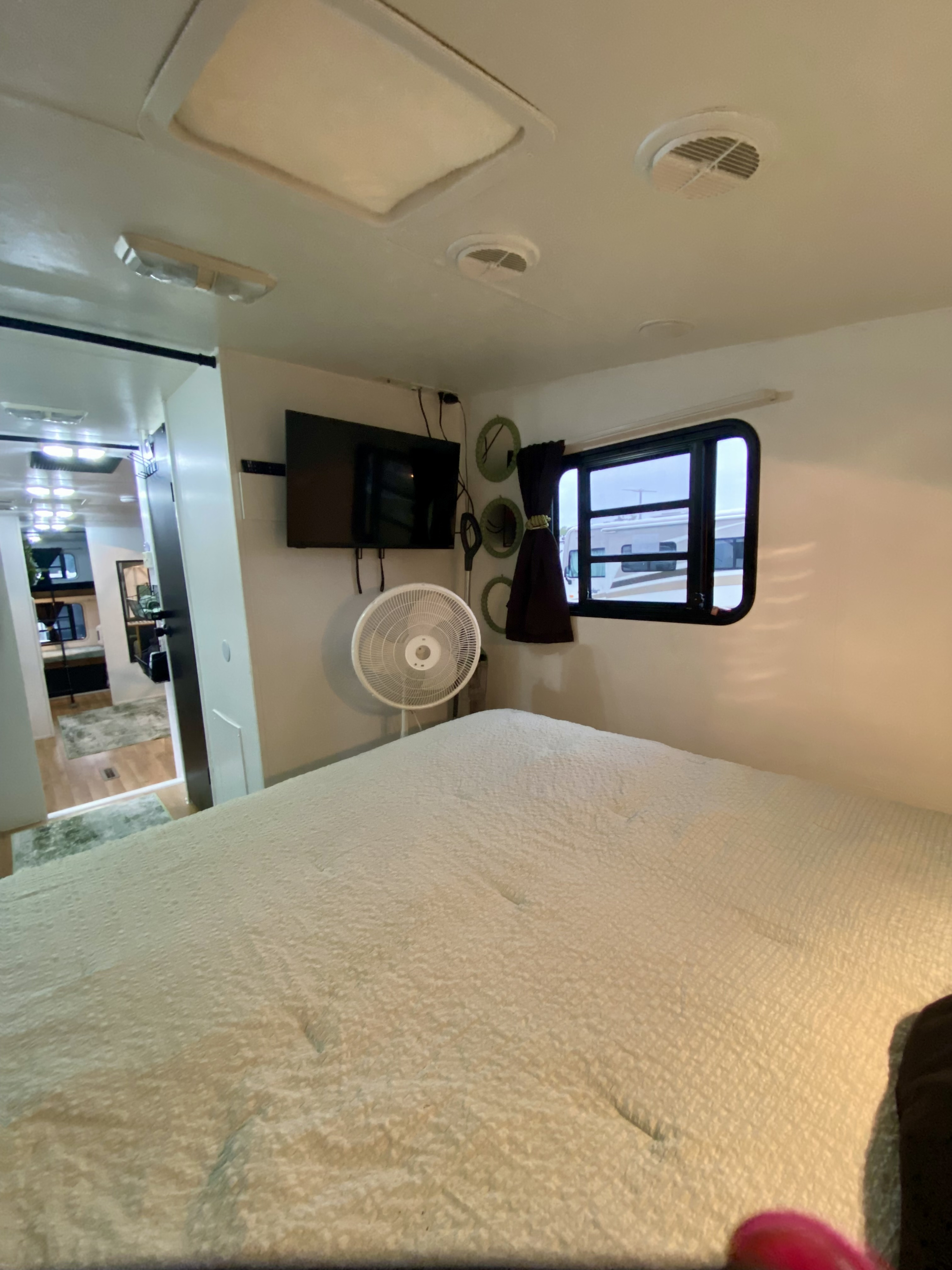 Cozy RV rental bedroom featuring a comfortable bed, wall-mounted TV, fan, and window, perfect for mobile living.. Jayco Eagle 2006