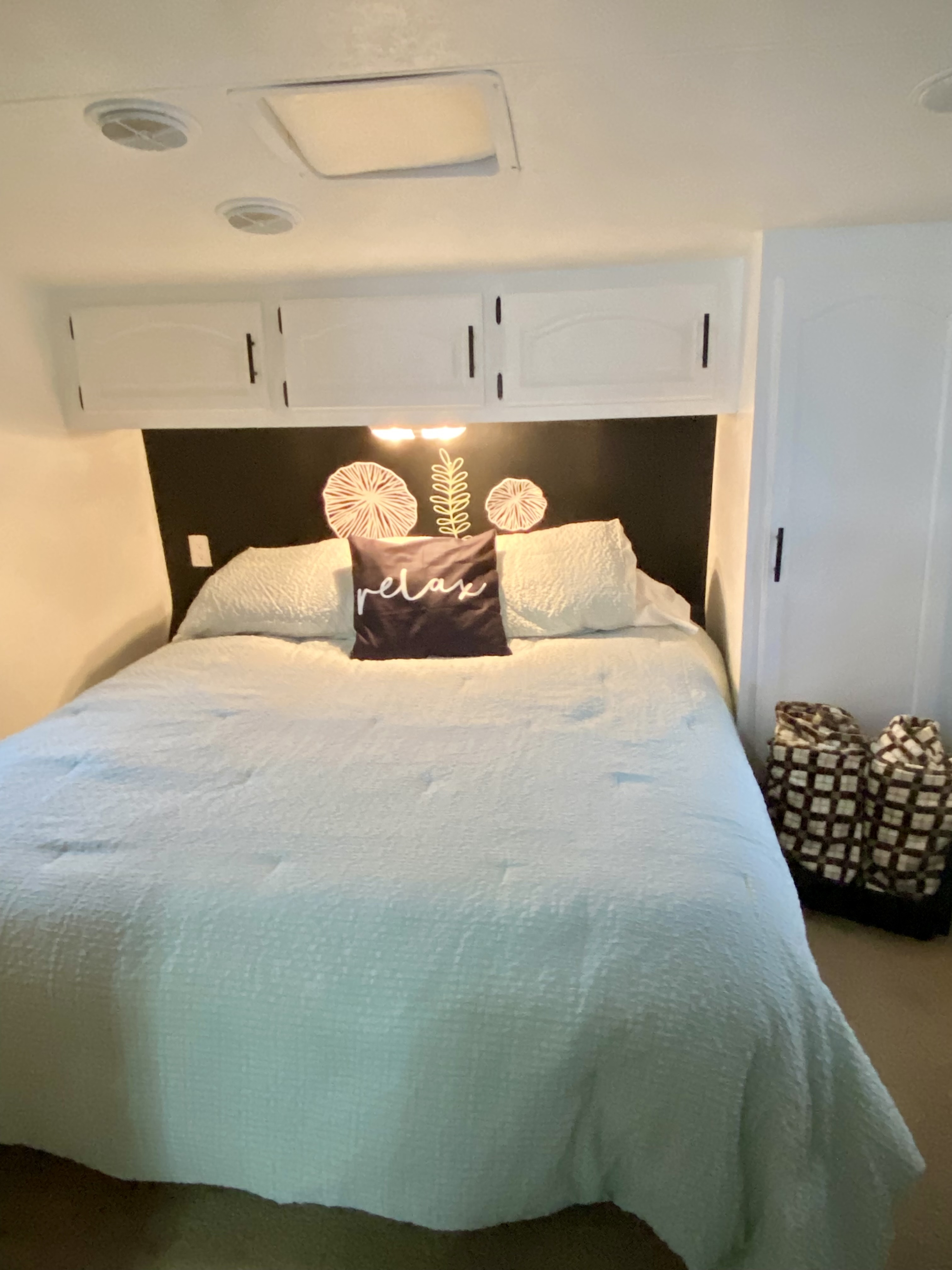 Serene RV rental bedroom: light blue bedding, "relax" pillow, and practical overhead storage cabinets create a cozy space.. Jayco Eagle 2006