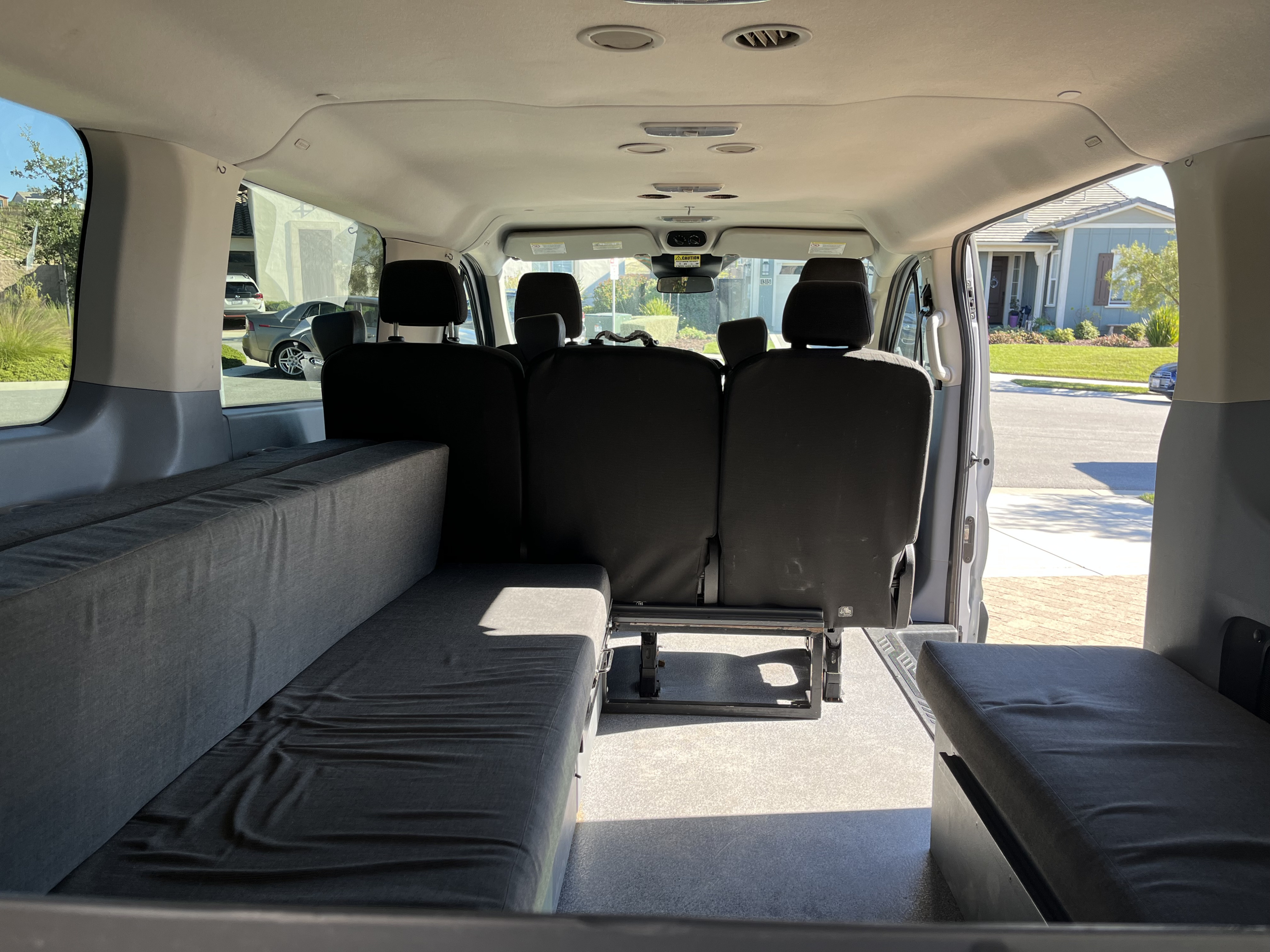 Inside an RV rental van: custom rear bench seating/beds and passenger seats, ideal for travel adventures.. Ford Custom Transit 2017