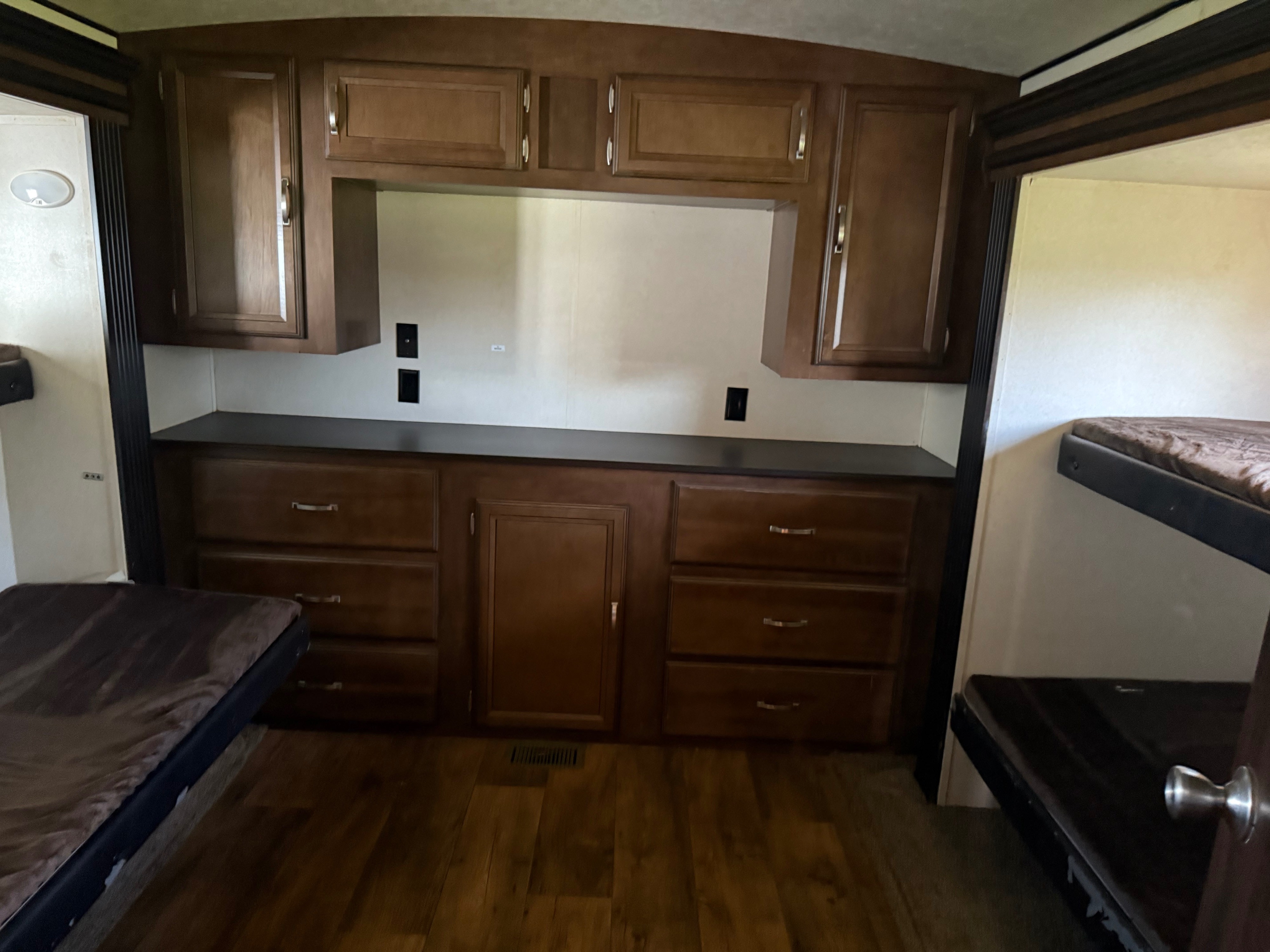 RV rental interior with wooden cabinetry, counter space, and cozy bunk beds on both sides, offering practical storage.. Forest River Wildwood Heritage Glen Lite 2018