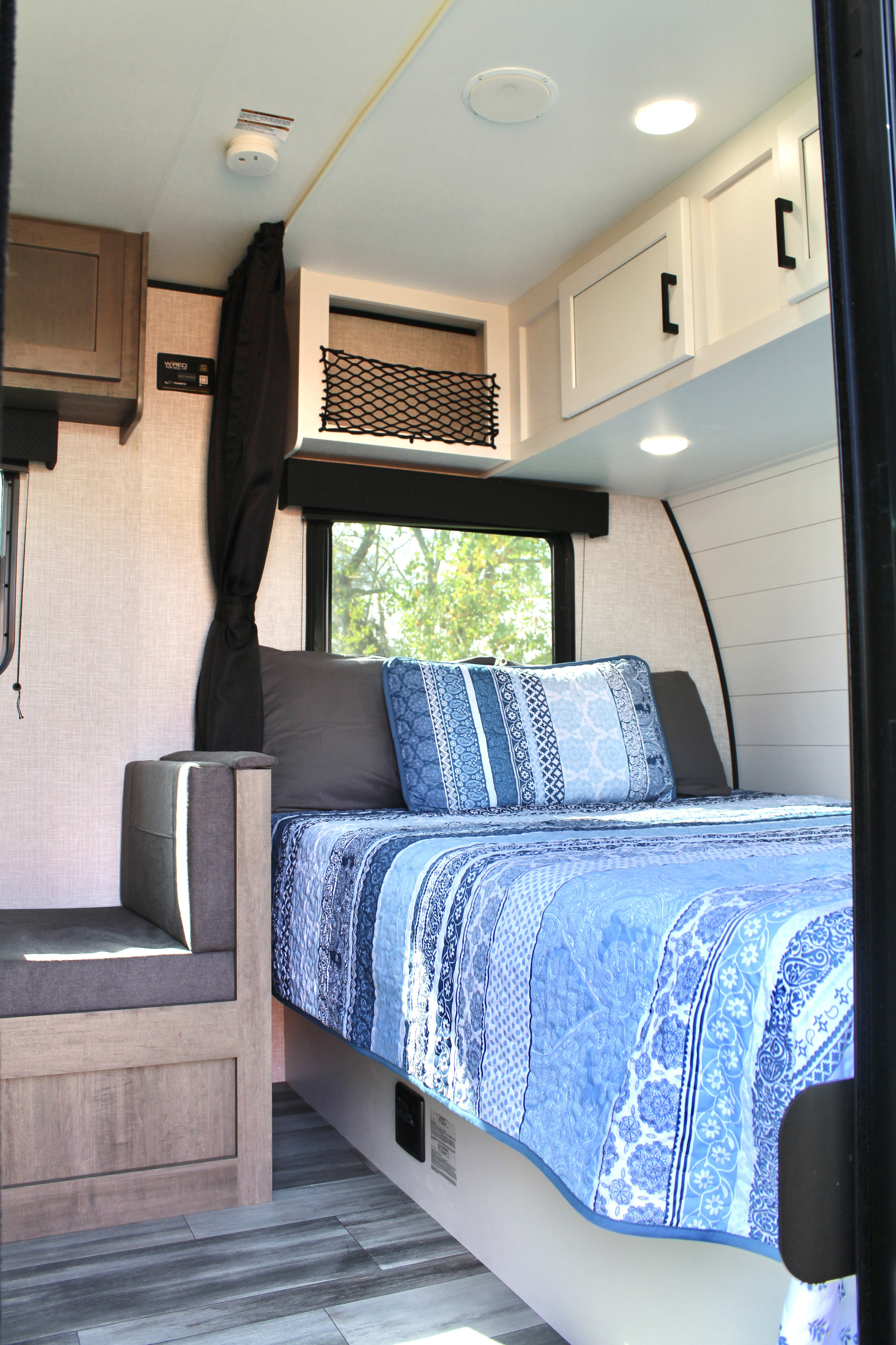 Cozy RV rental bedroom featuring a blue quilt, window view, and ample storage for comfortable travel.. Jayco Jay Flight SLX 2024