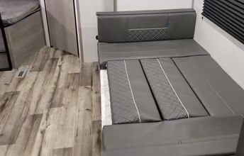This RV rental's gray sofa converts to a comfortable bed, providing extra sleeping space inside this modern travel trailer.. Dutchmen Coleman Lantern 2022