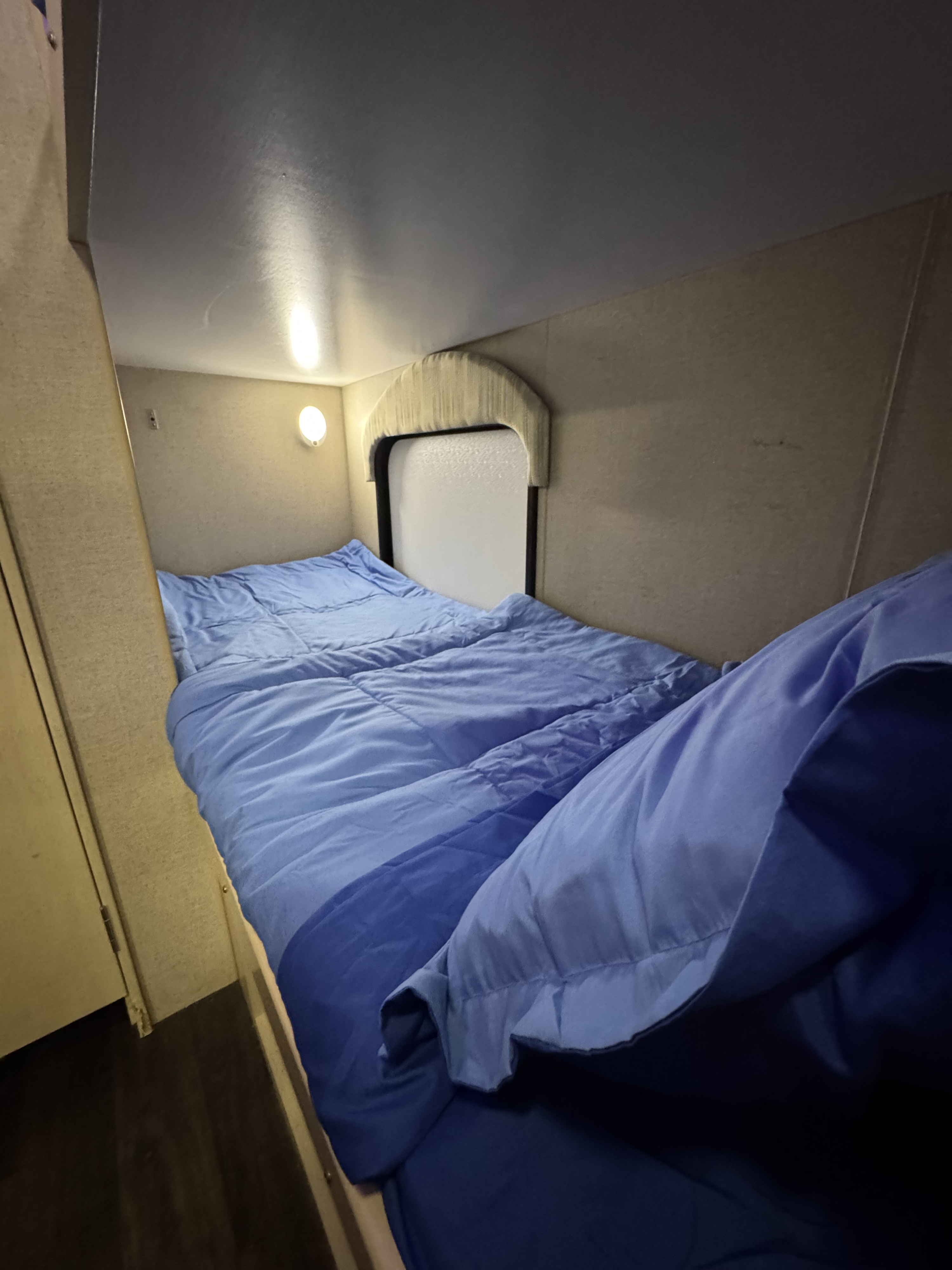 RV rental bunk bed: a snug sleeping space with blue bedding, wall light, and small window.. Winnebago Micro Mini 1700BH 2019