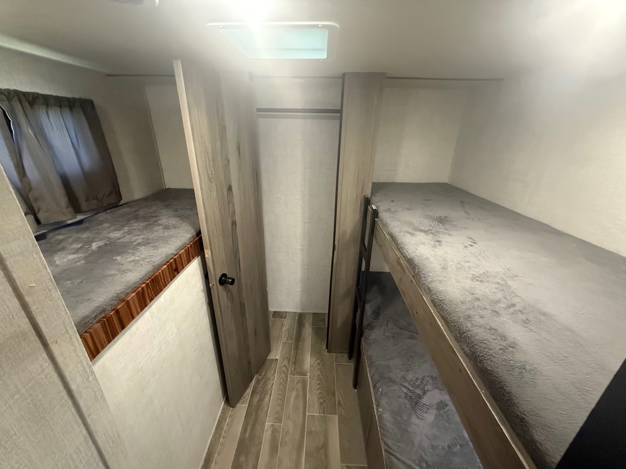 RV rental bunkhouse: stacked beds & a lower bed with soft grey bedding, plus a small closet/wardrobe area.. Gulf Stream Kingsport 2021