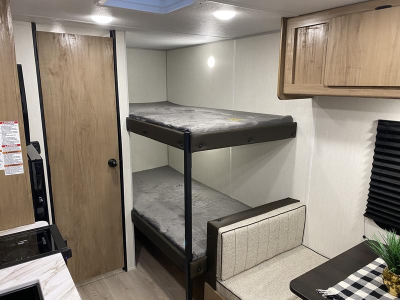RV rental interior: cozy bunk beds, compact kitchen counter, and dinette with seating for comfortable travel.. Forest River Cherokee Wolf Pup 2025
