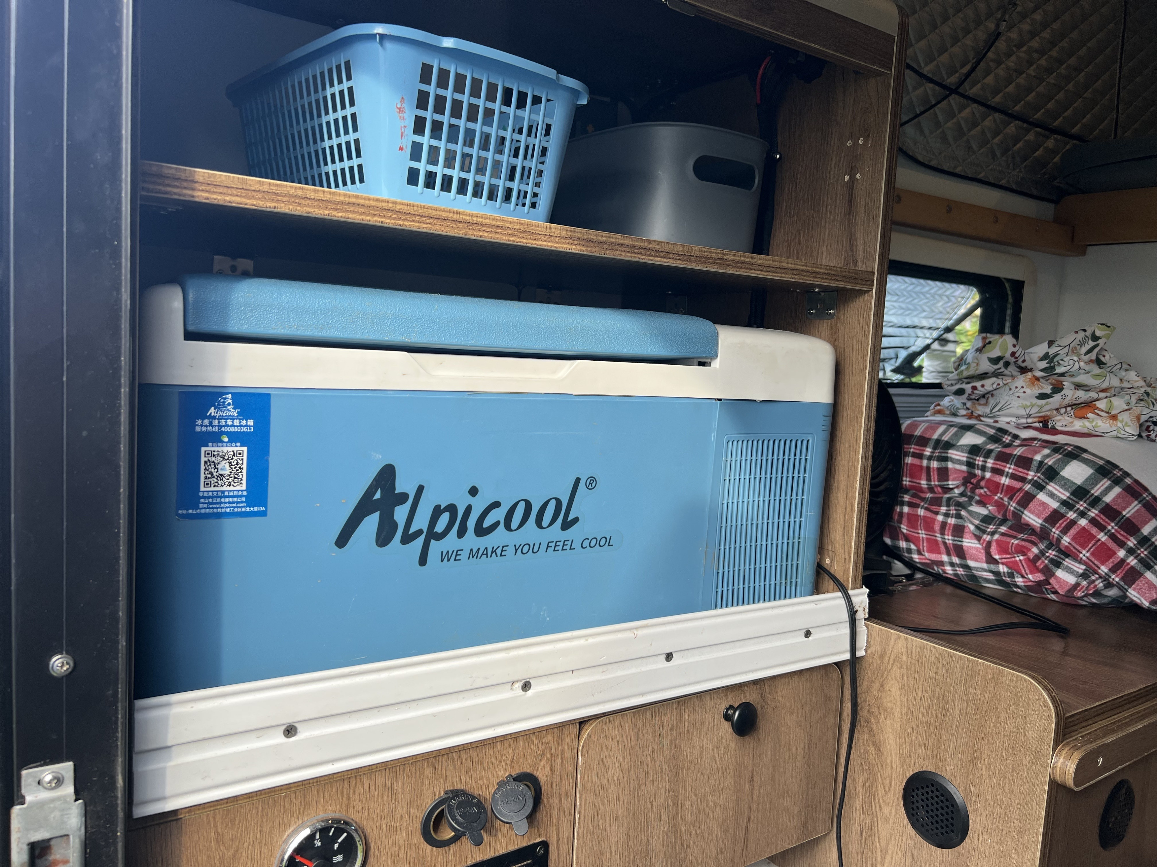 Compact Alpicool portable fridge-freezer on a slide-out in an RV rental, with storage, blankets, and power ports.. toyota trd 4x4 sport 2017