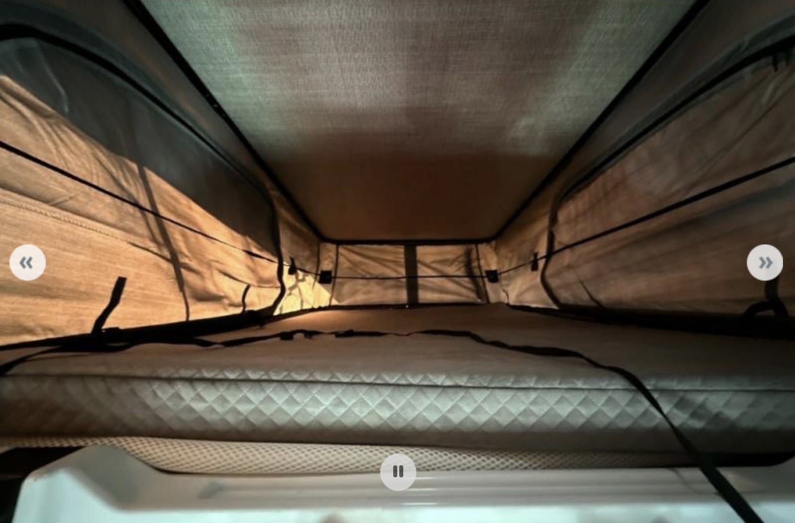 Cozy pop-top sleeping area in an RV rental, featuring a quilted mattress and canvas walls, perfect for comfortable camp travel.. Winnebago Solis 2025